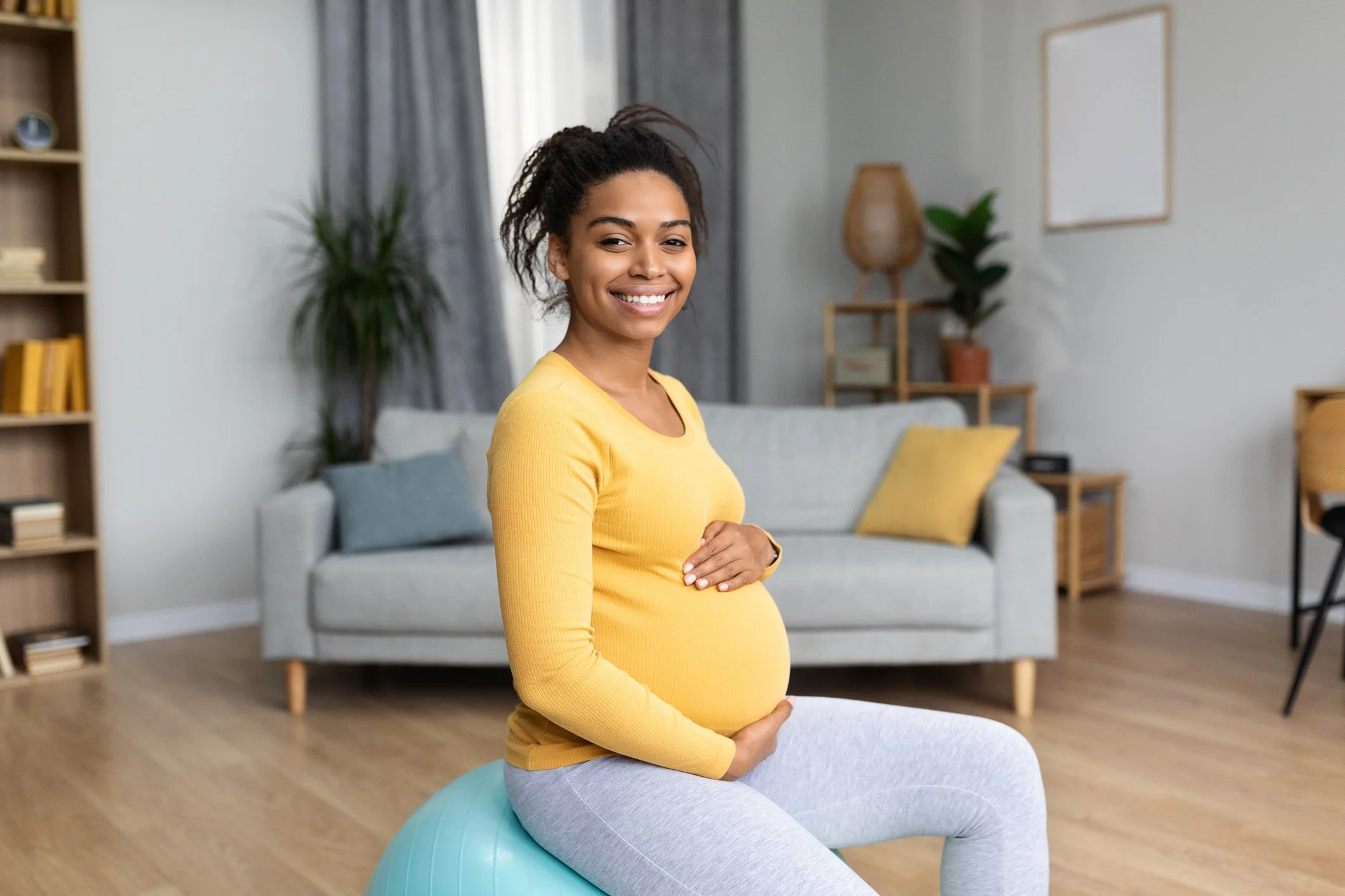 a pregnant woman holds her belly and smiles