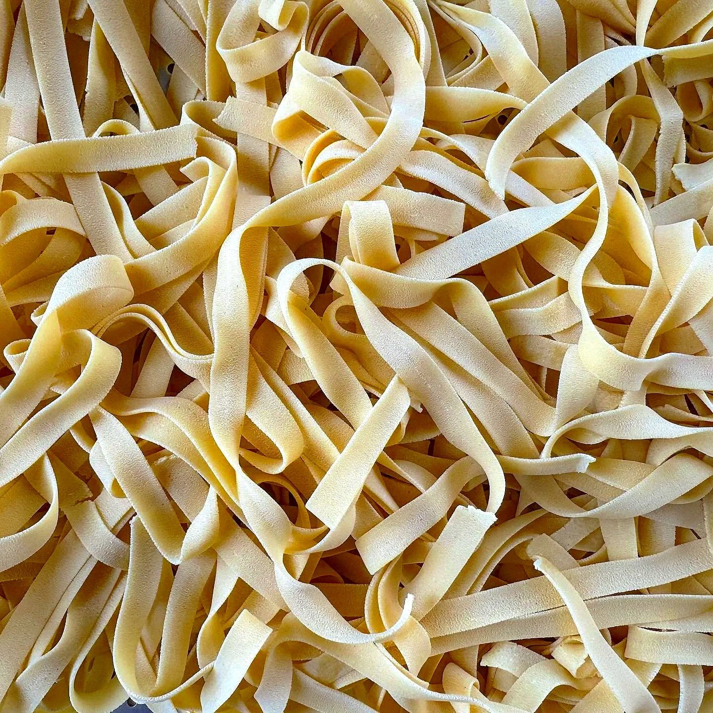 Close-up of uncooked fettuccine pasta noodles scattered on a surface.