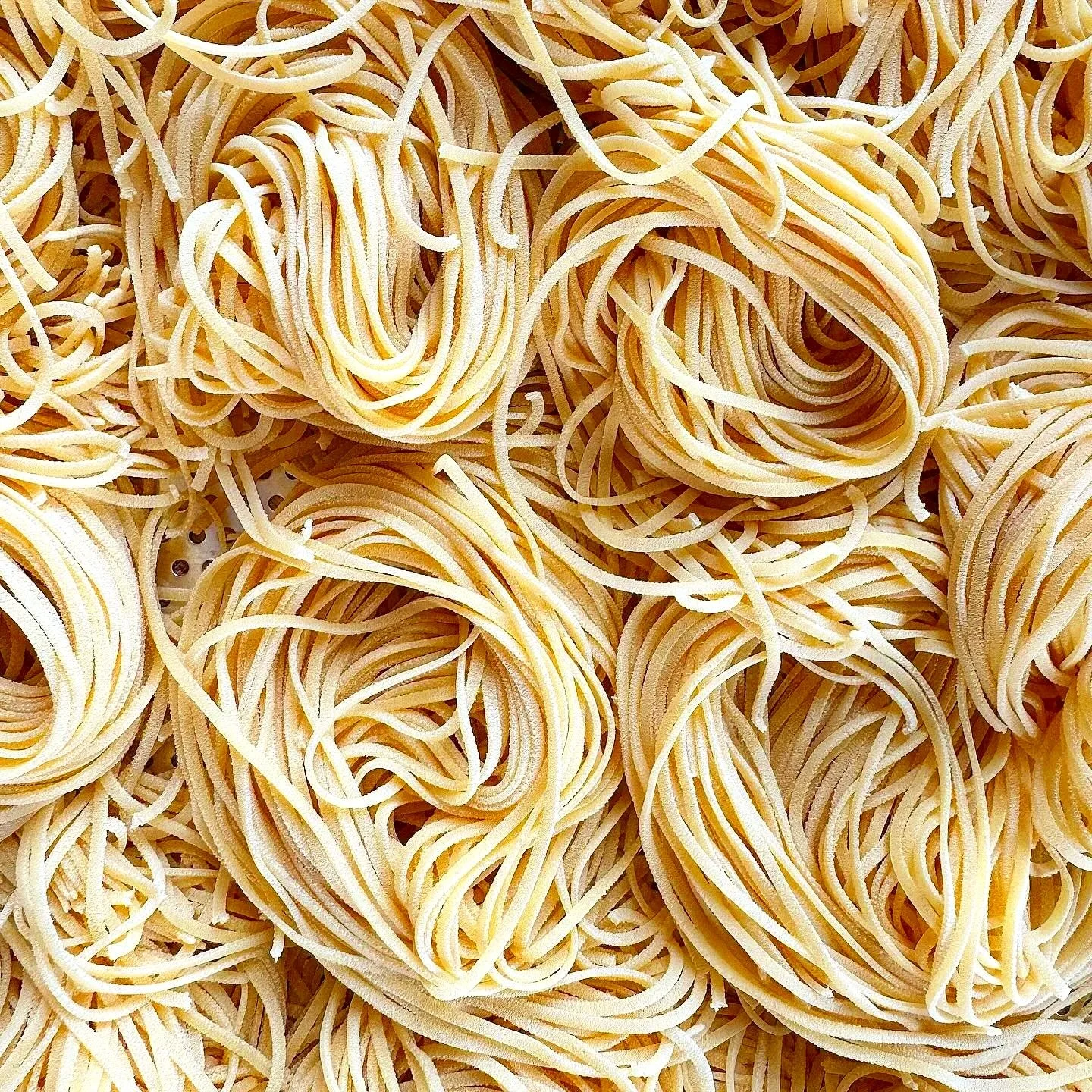 Close-up of uncooked, yellow, spaghetti pasta noodles tangled together.