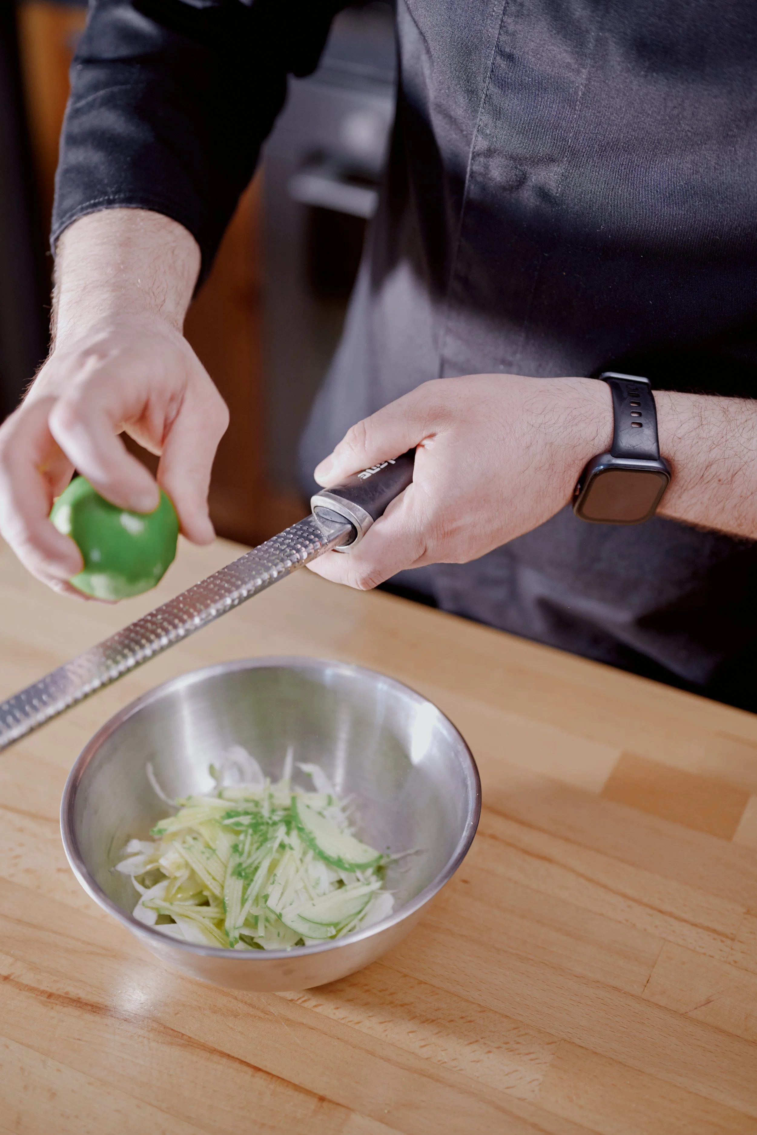 Un chef coupe des légumes avec une râpe dans une cuisine.