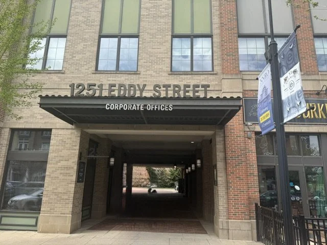 Building entrance at 1251 Eddy Street with a sign for Corporate Offices, glass windows, and a street view.