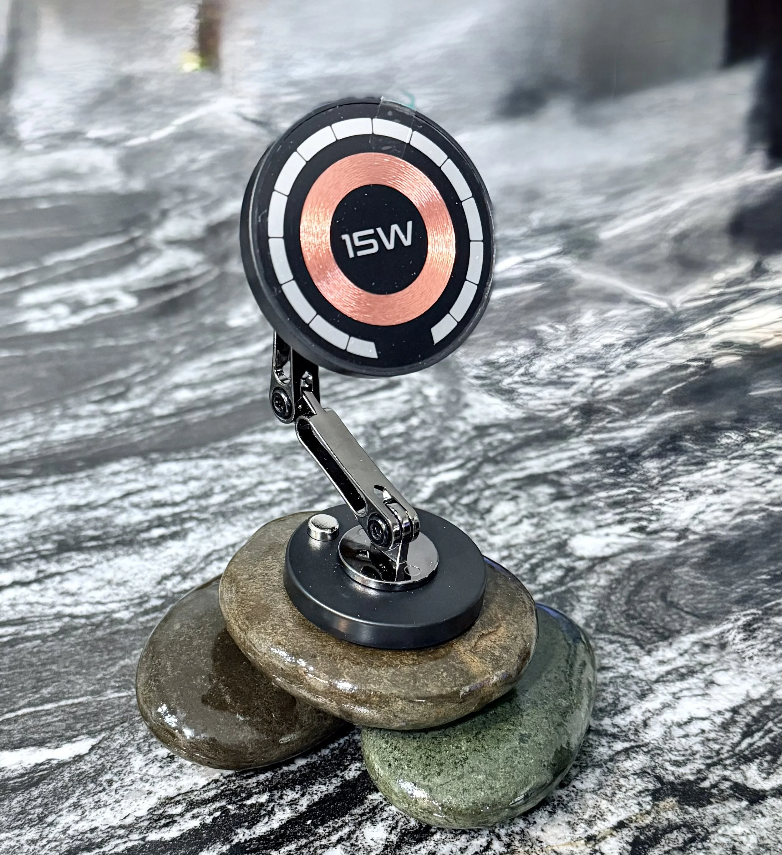 A fishing reel with a 15-watt power indicator, mounted on rocks near a water body, with water and rocks in the background.