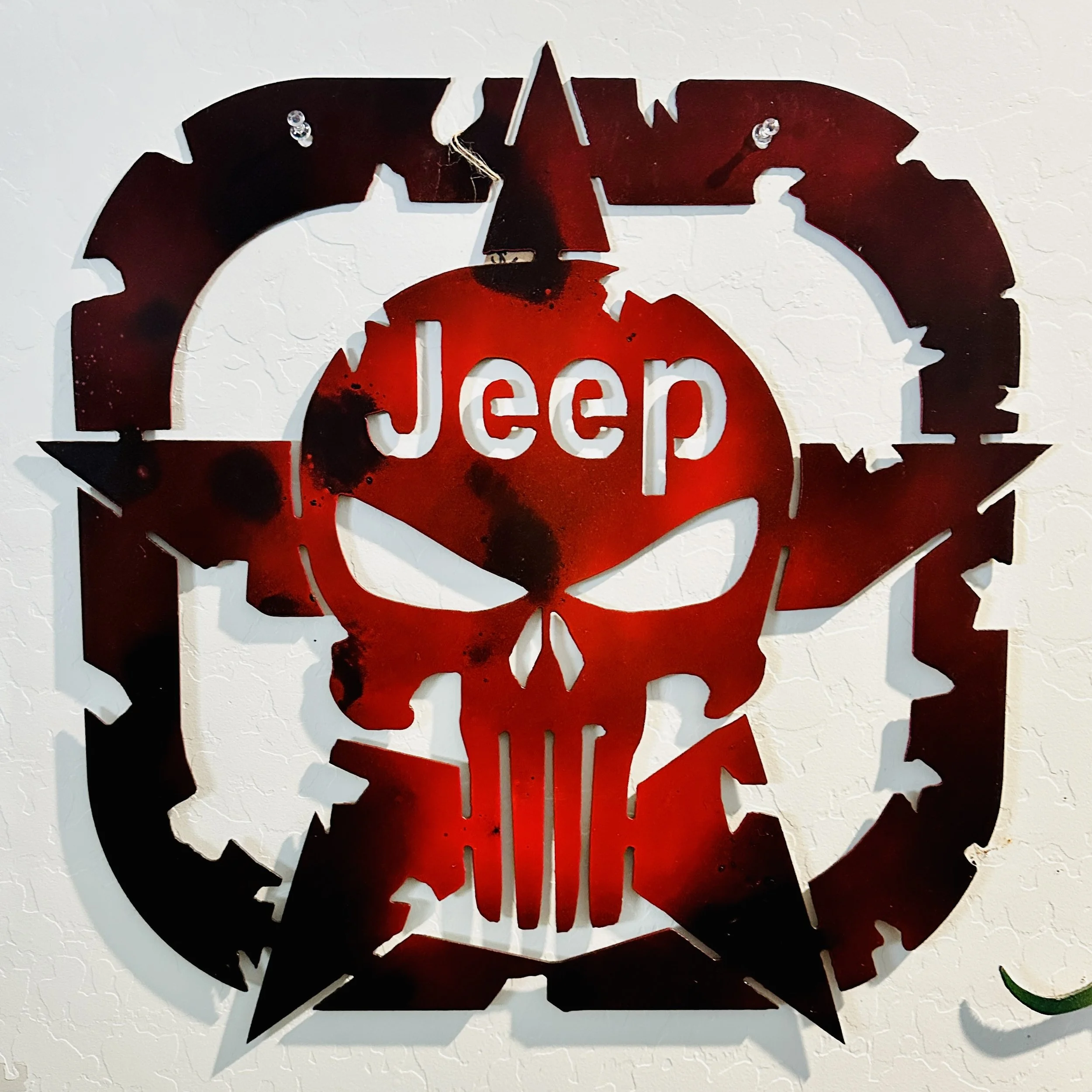 Decorative wall art featuring a black and red skull design with the word 'keep' in the middle, mounted on a textured white wall.