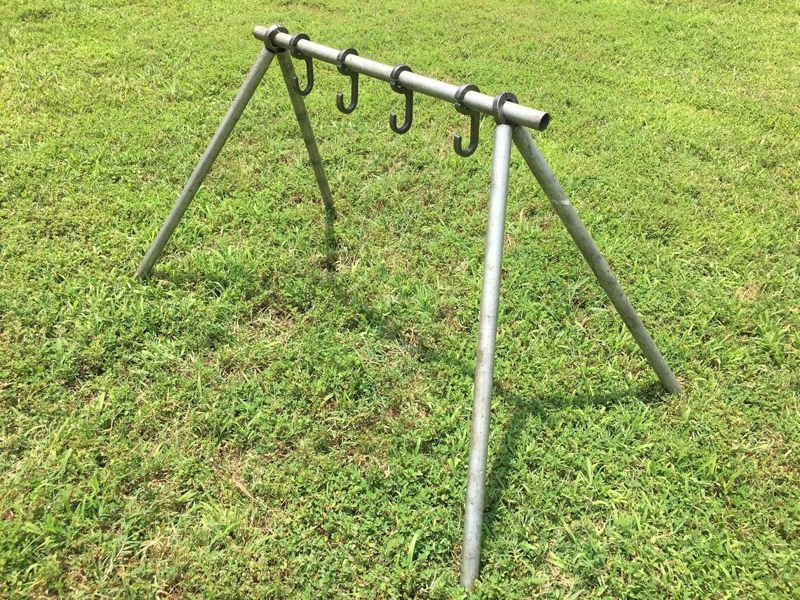 Metal playground structure with hooks, standing on a grassy field.
