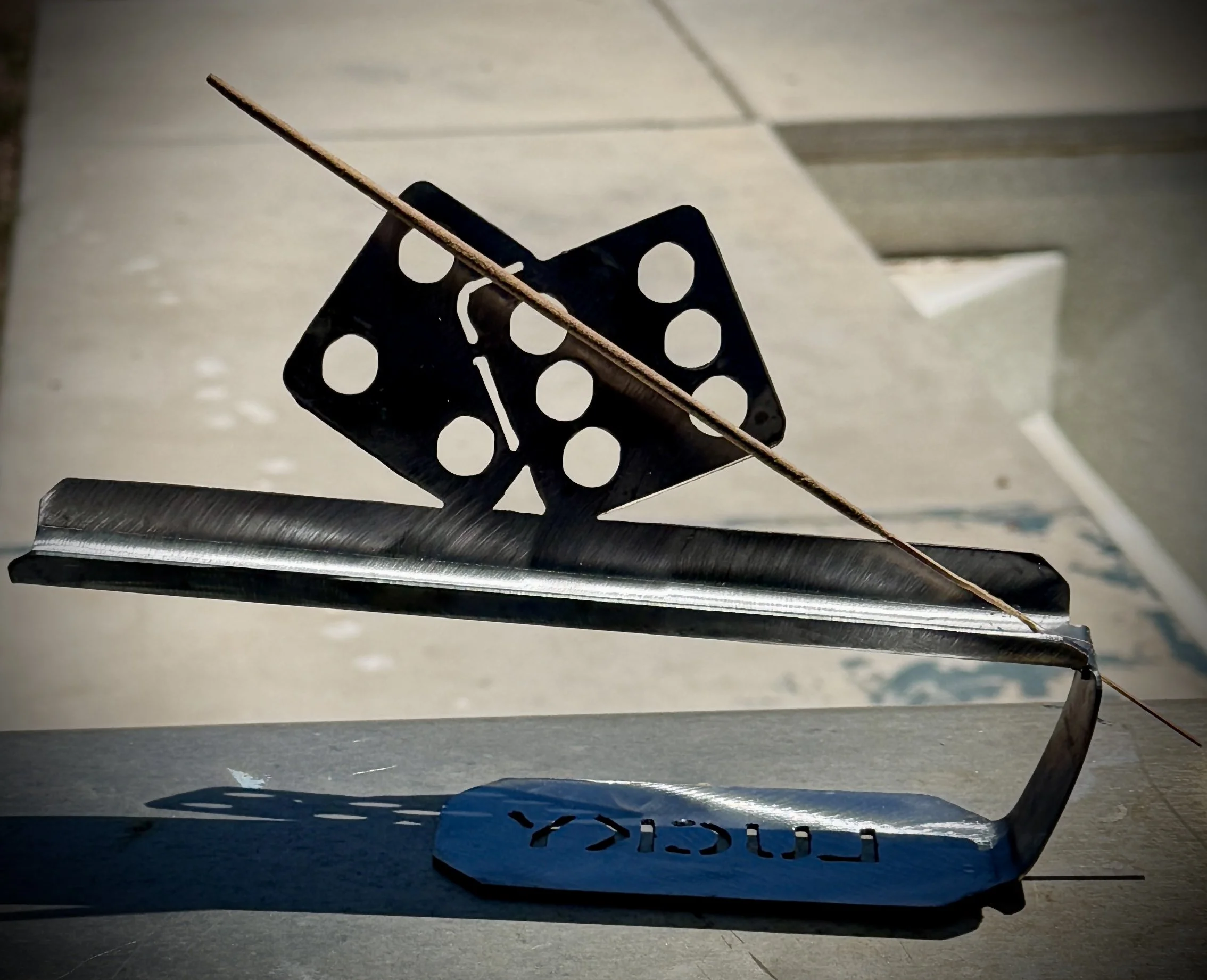 Close-up of a black chess piece and a wooden stick on a gray surface with a blurred background.