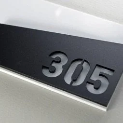 Close-up of a black address plaque with silver numbers 305