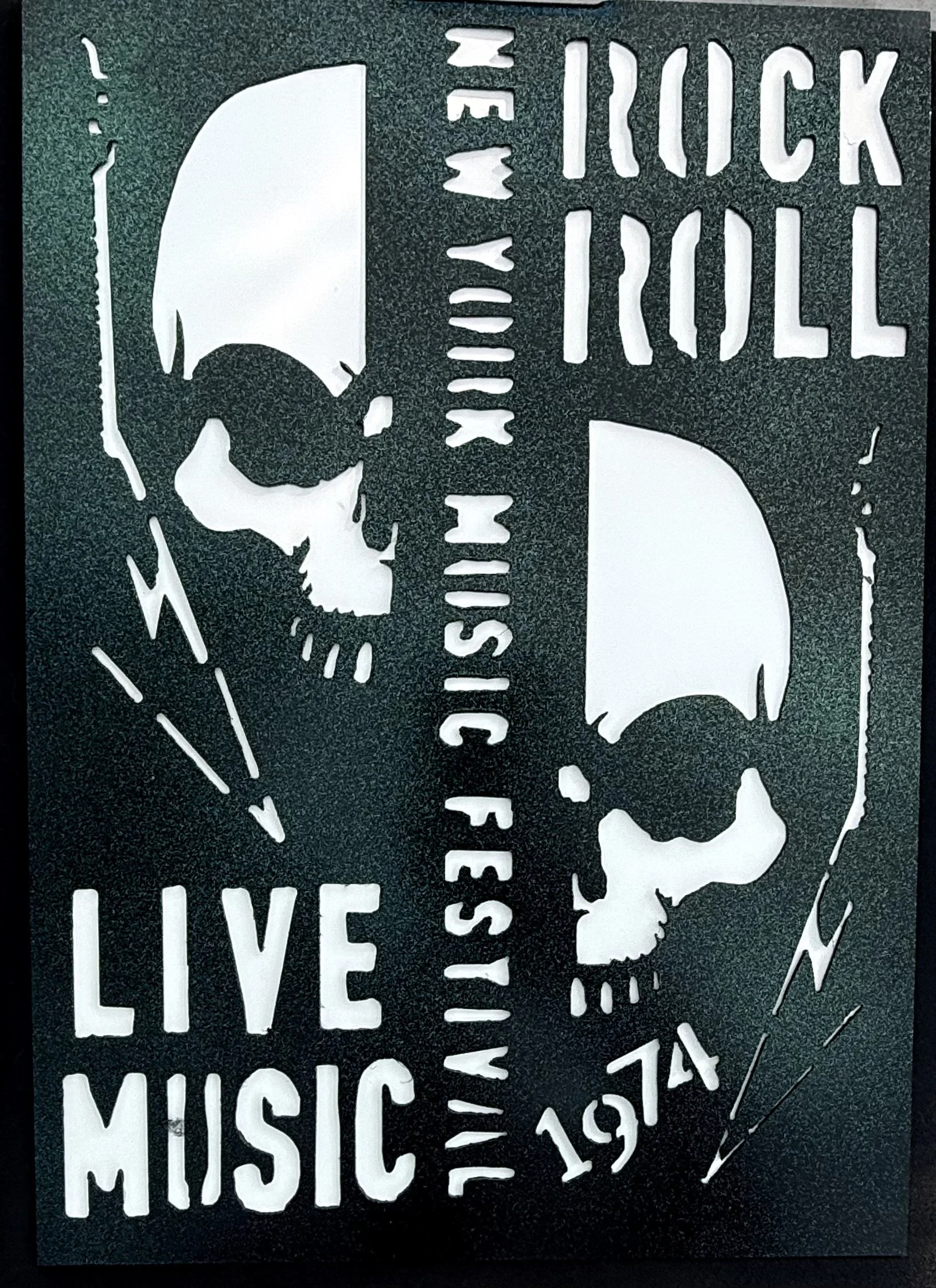 Cut-out stencil art of a skull, a guitar, and text that reads 'Rock & Roll' and 'Music' on a black background.