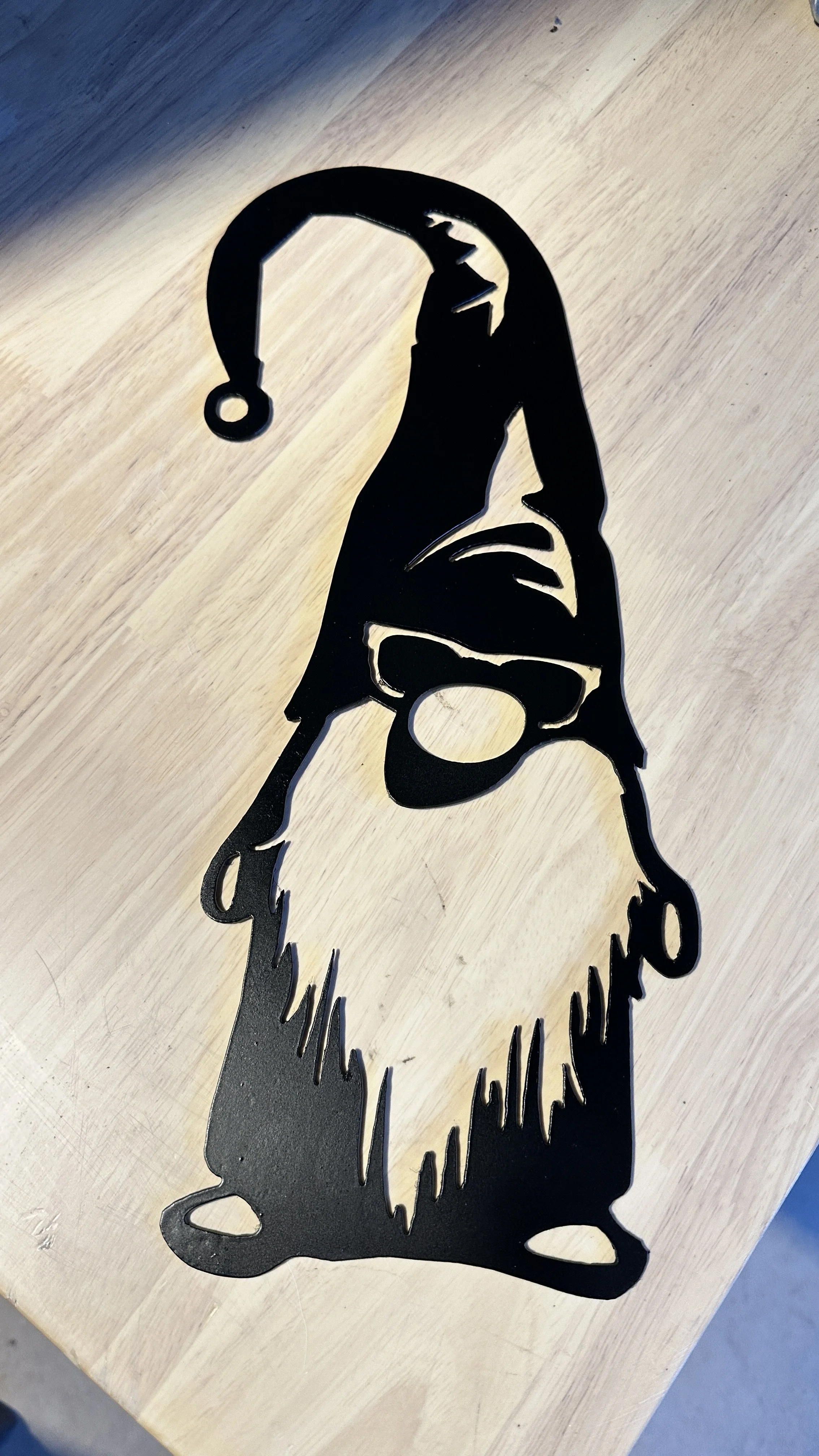 Metal artwork of a dog wearing a Santa hat placed on a wooden surface.