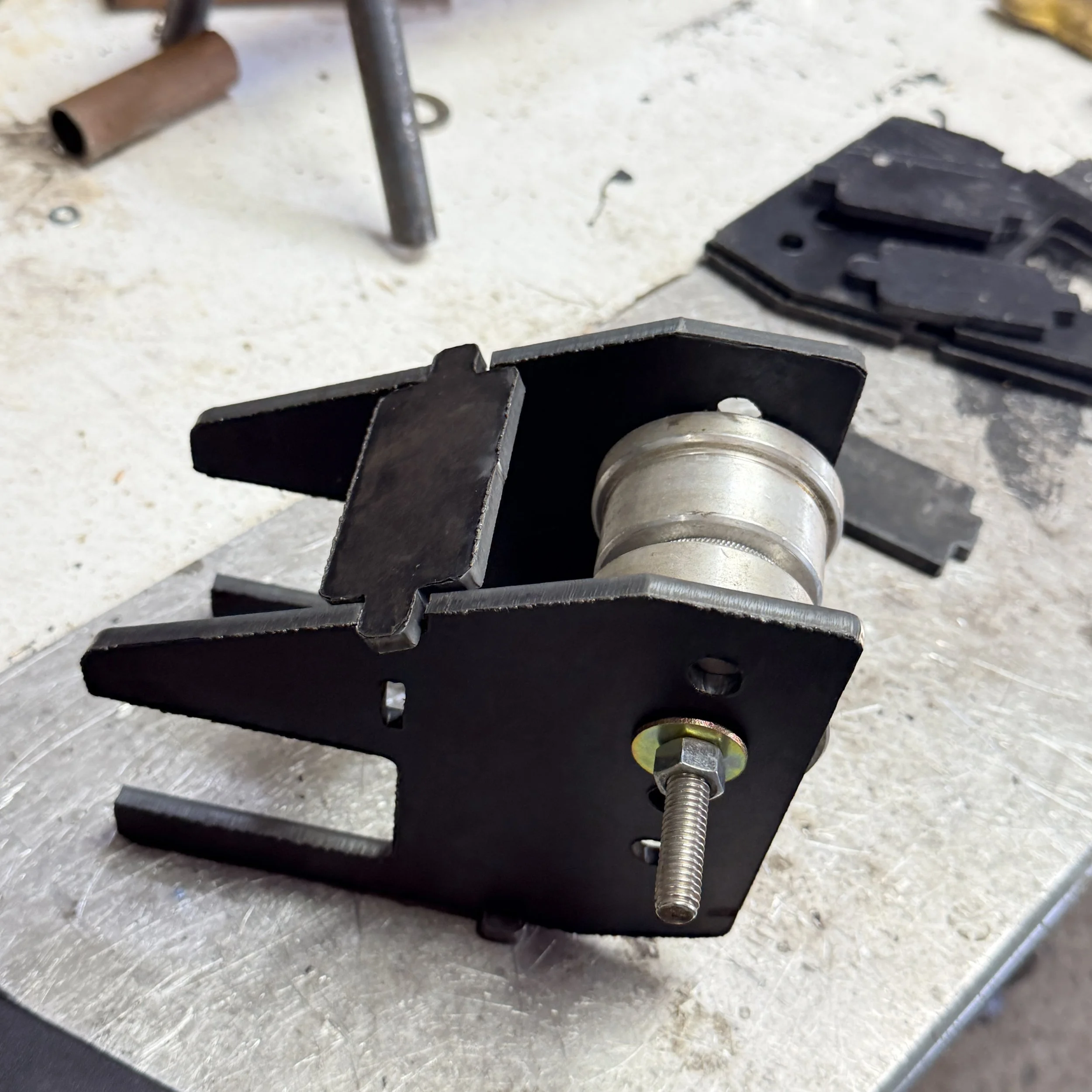 Close-up of a mechanical brake caliper on a vehicle, showing metal components and mounting hardware.