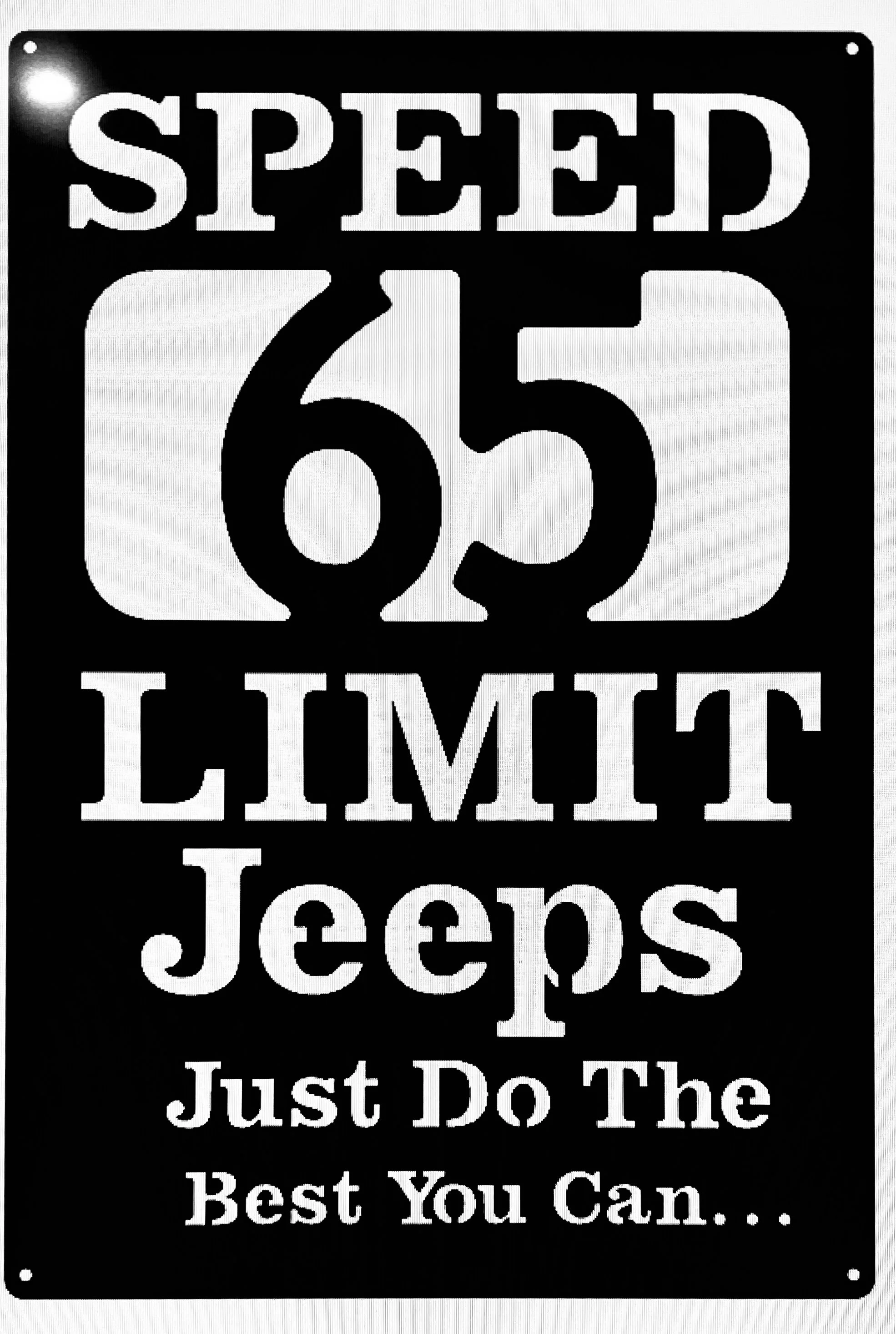 A black and white sign with the phrase 'Speed 65, Limit, Just Do The Best You Can...' in bold letters.