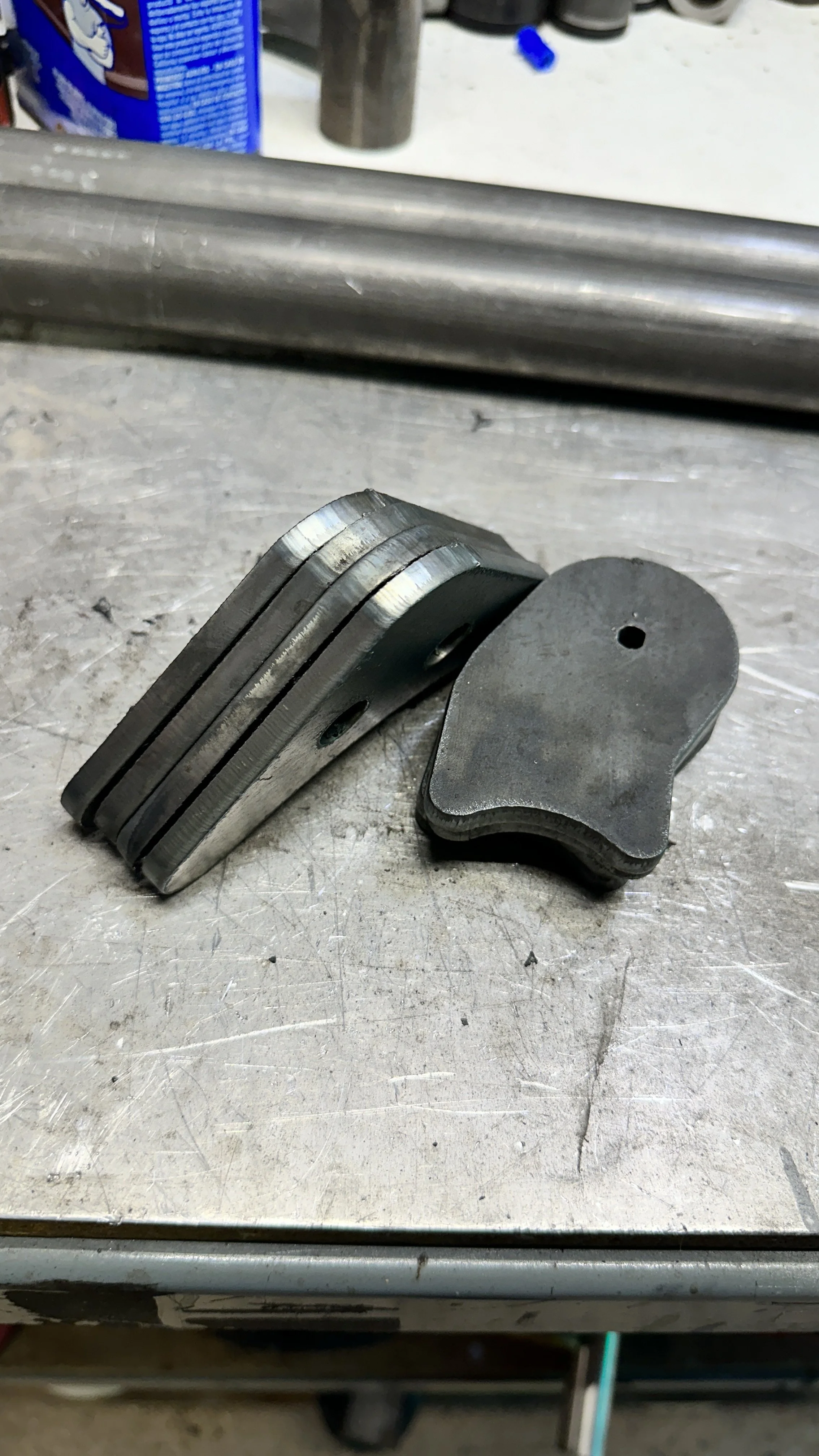 A set of metallic brake pads stacked together on a work surface, with a brake rotor in the background.
