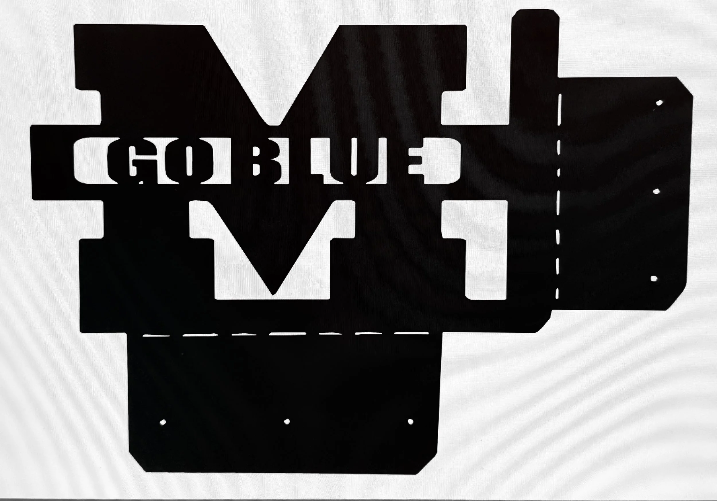 Backlit stencil art of the word 'GOBLIN' in bold letters, on a sign mounted to a dark surface.