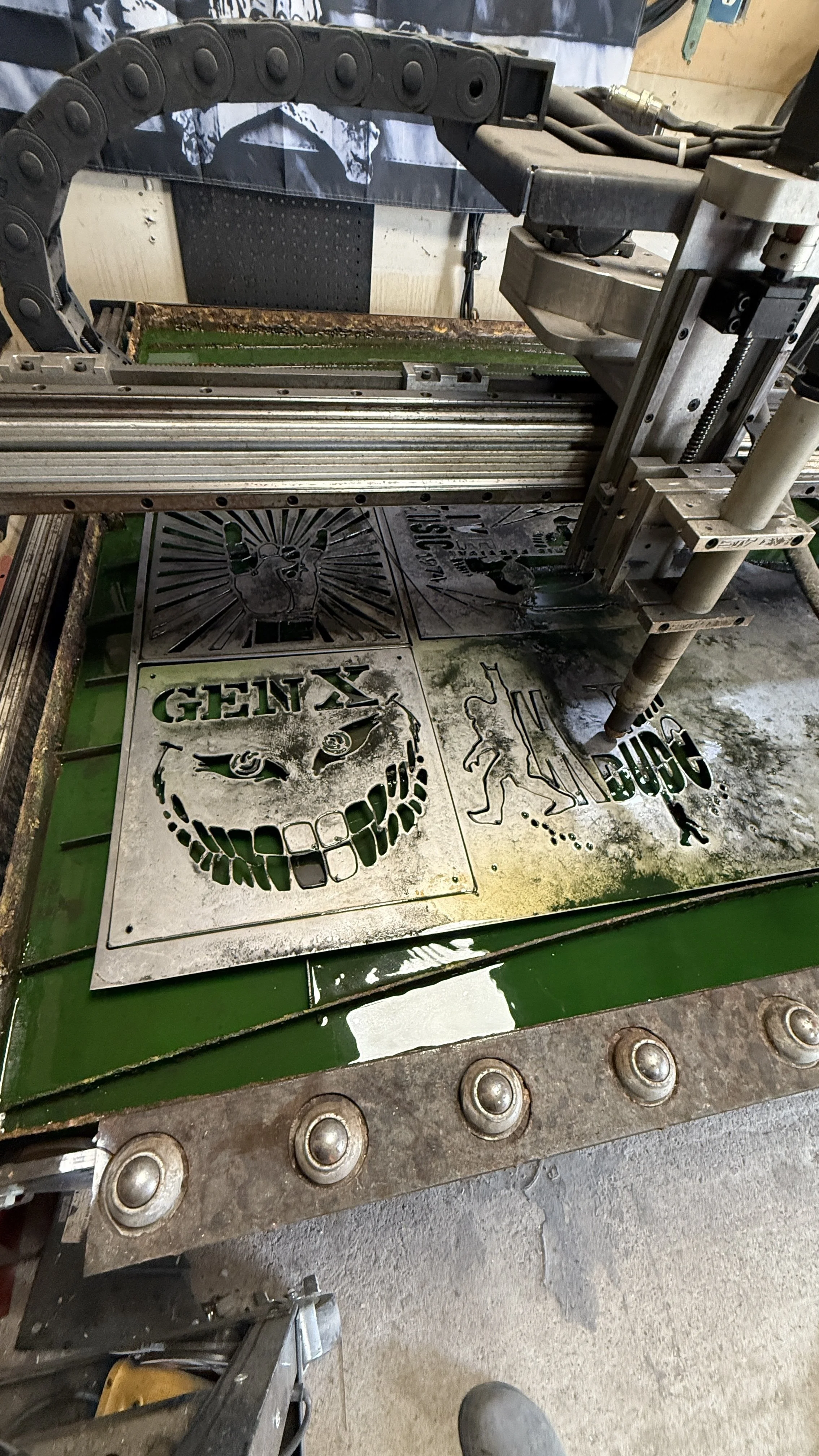 A metal cutting machine with cutout designs of a skull, a lion, and the word 'GEIX' on the surface.