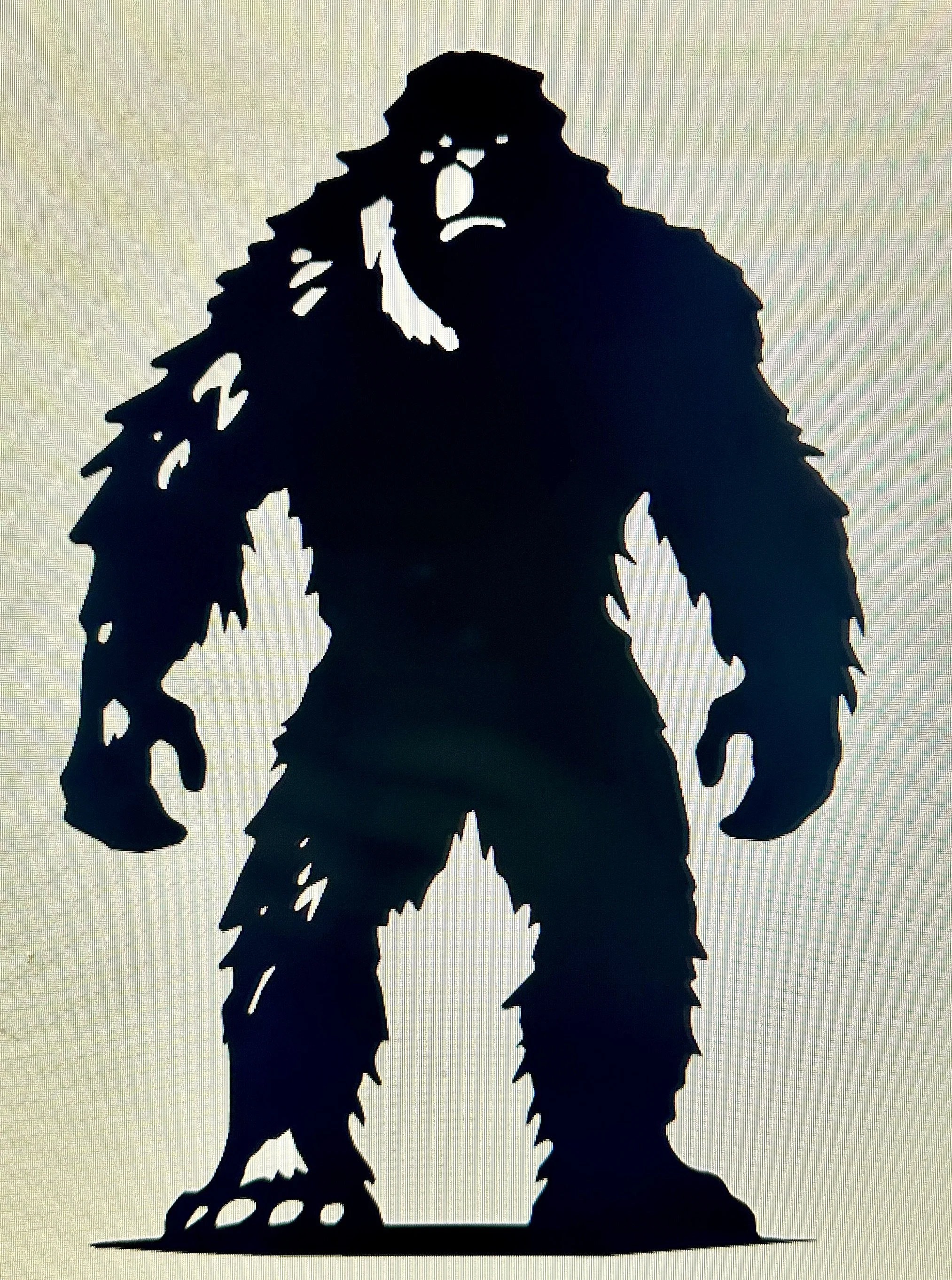 Silhouette of a Bigfoot or Sasquatch figure standing on a flat surface, with tall legs, long arms, and shaggy fur, against a light background.