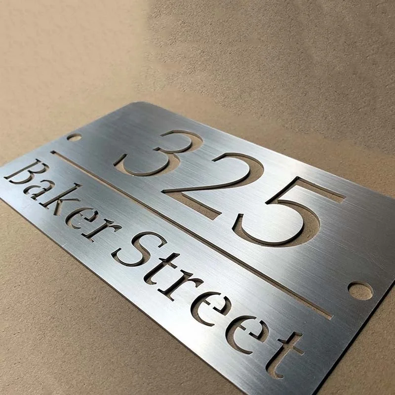 A metallic address plaque displaying the house number 1325 and the street name Baker Street, mounted on a beige wall.