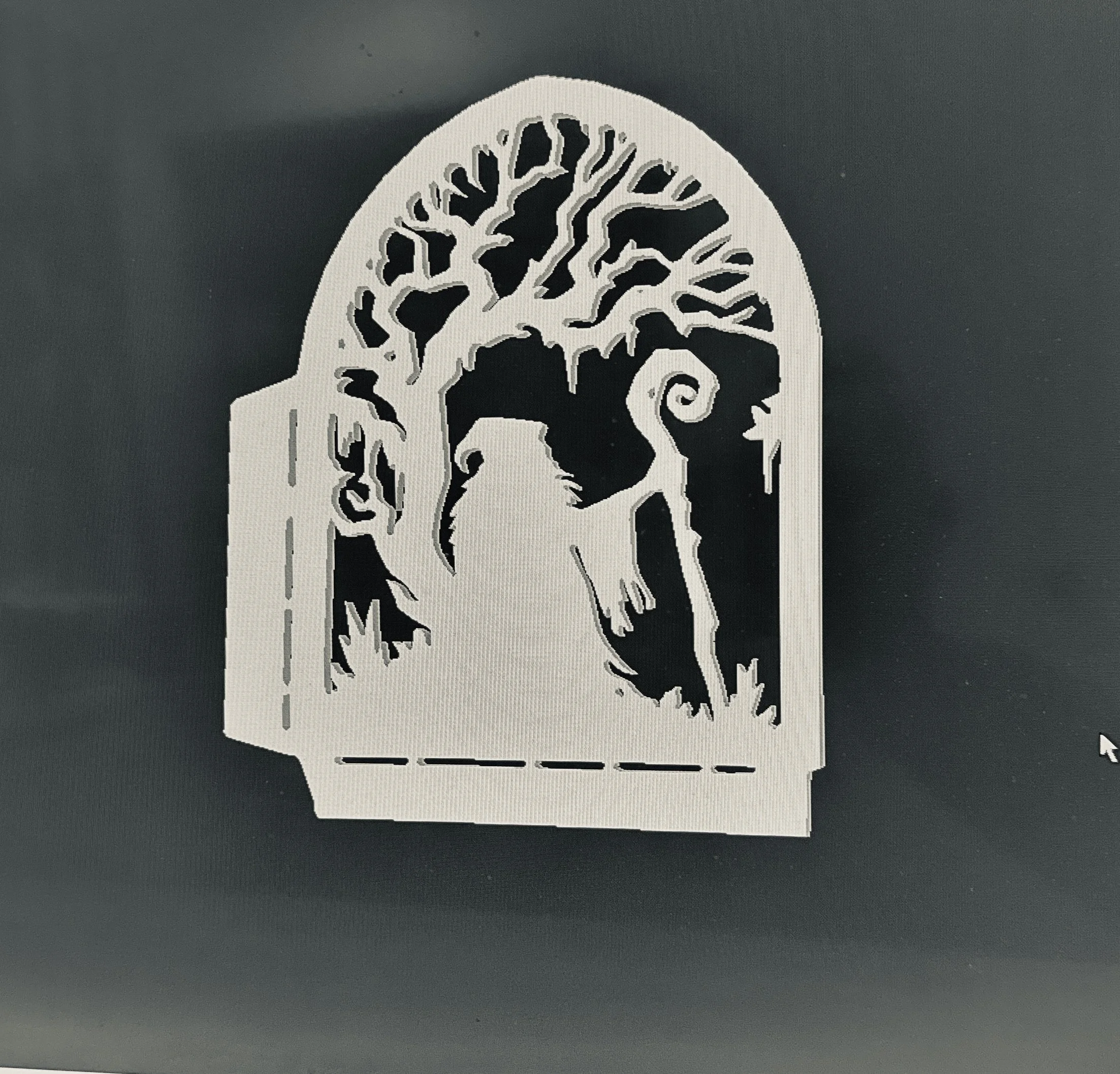 A white paper cutout of a tree with many branches and roots, placed on a dark surface.