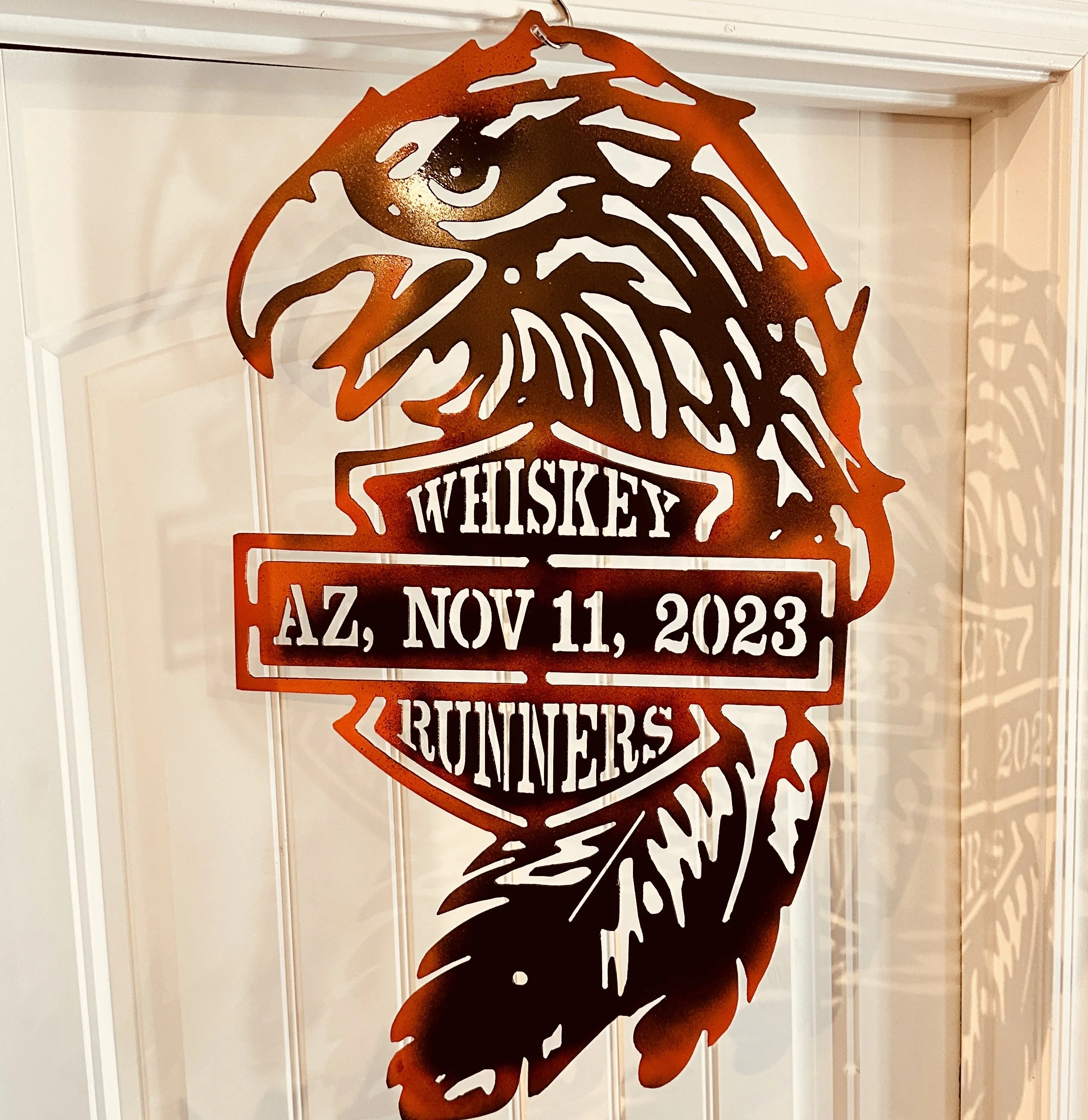 A rust-colored metal sign in the shape of a wolf's head with the word 'WHISKEY' and date 'AZ, NOV 11, 2023' written below.