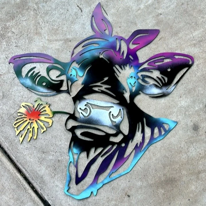Colorful metal wall art of a dog with a flower next to it, placed on a concrete surface.
