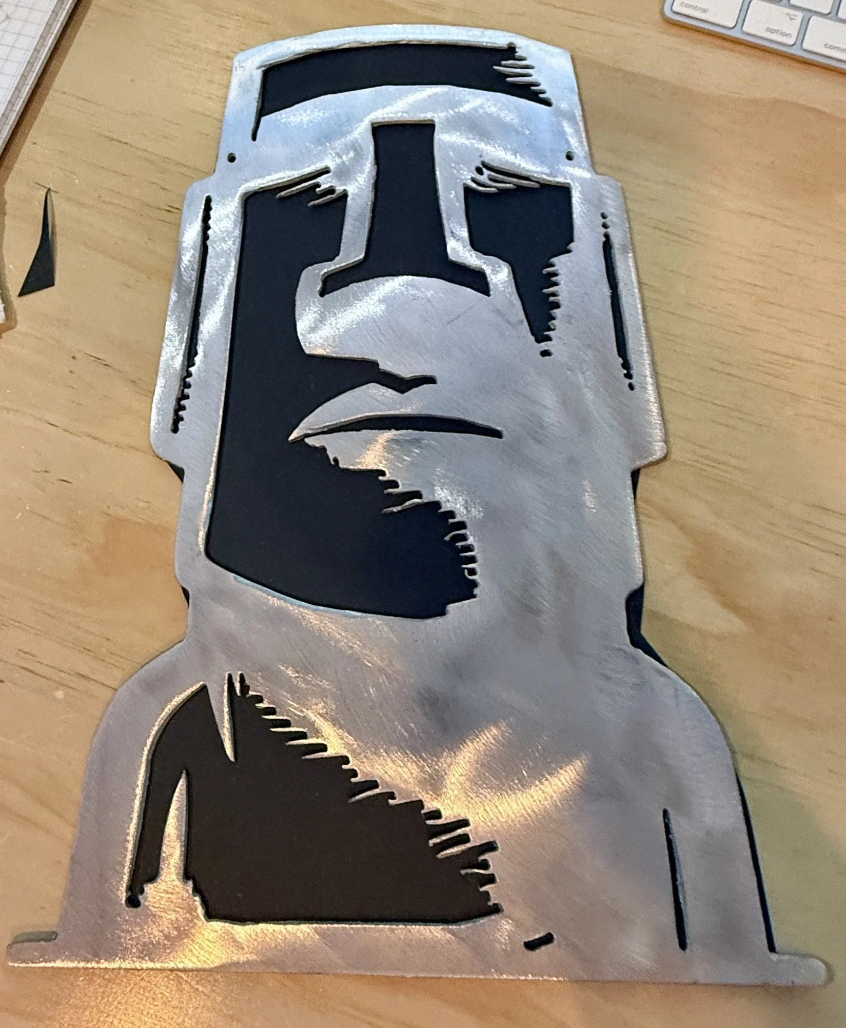 Metal cutout of Baby Yoda from Star Wars, placed on a desk with a keyboard and notepad nearby.