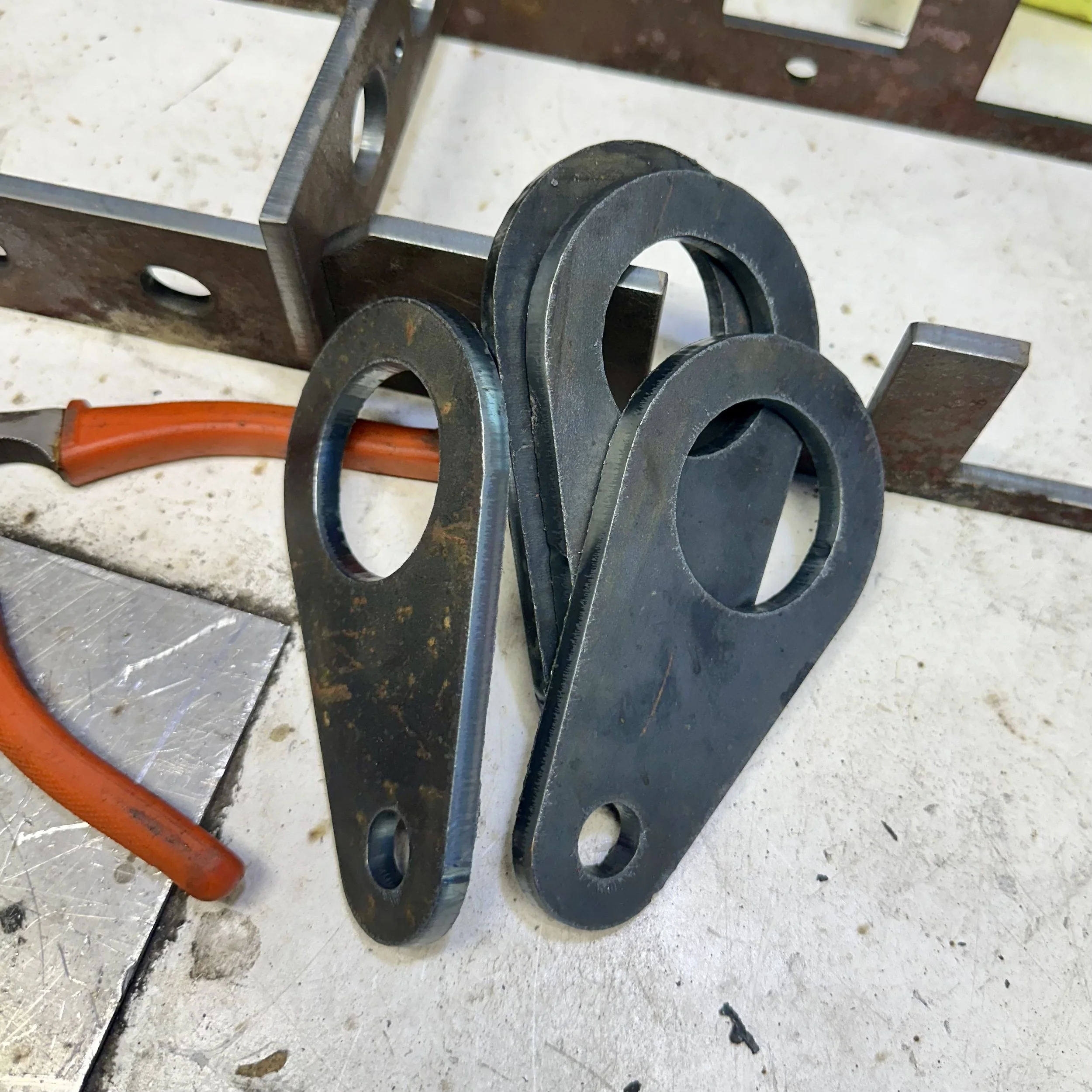 Close-up of metal washers and metal pieces on a workbench with an orange tool nearby.