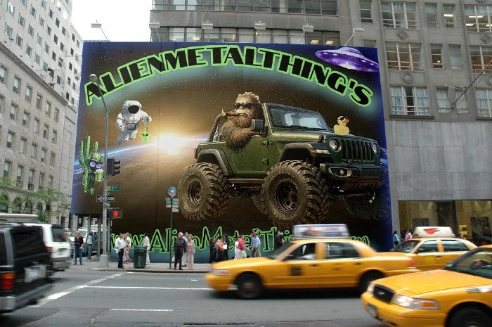 Urban scene with a large billboard advertising Alien Metal Things featuring a spaceship, astronaut, alien, a beard man in a vehicle, and a duck, with city skyscrapers and yellow taxis in the background.