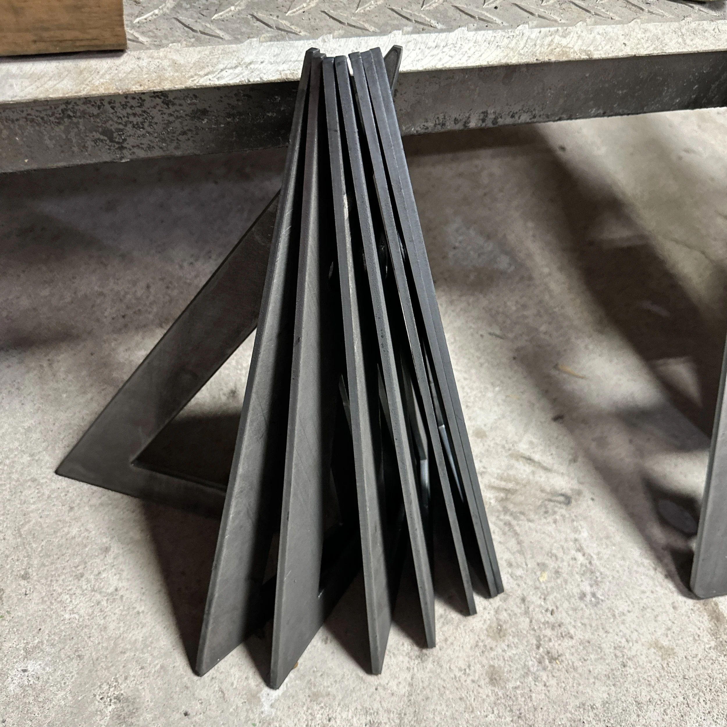 A stack of gray work or shovel blades leaning against a concrete ledge in an industrial or workshop setting.