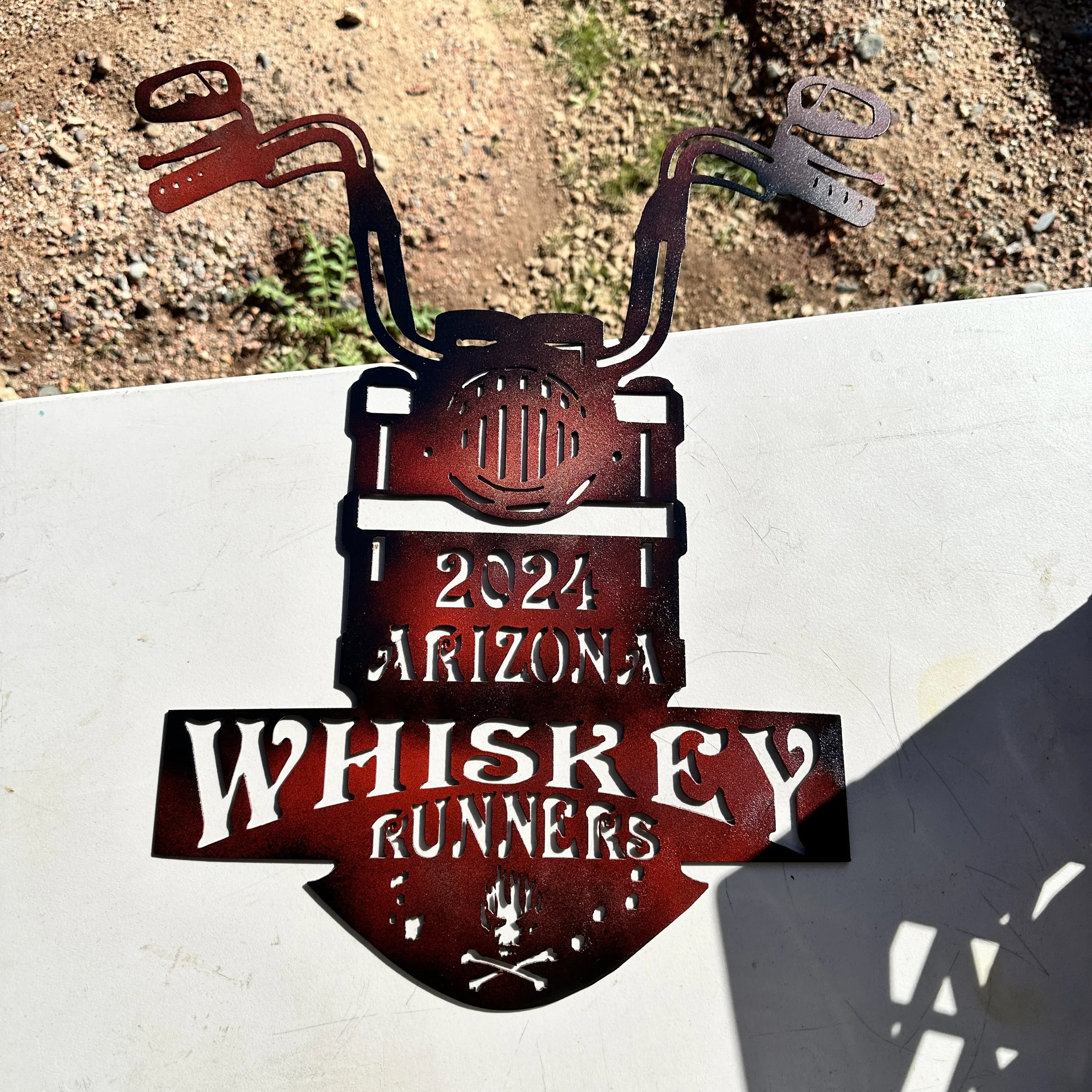Metal decoration of a cowboy with a lasso, the words "Wyoming" and a mountain range cutout, placed on a white surface with a desert background.