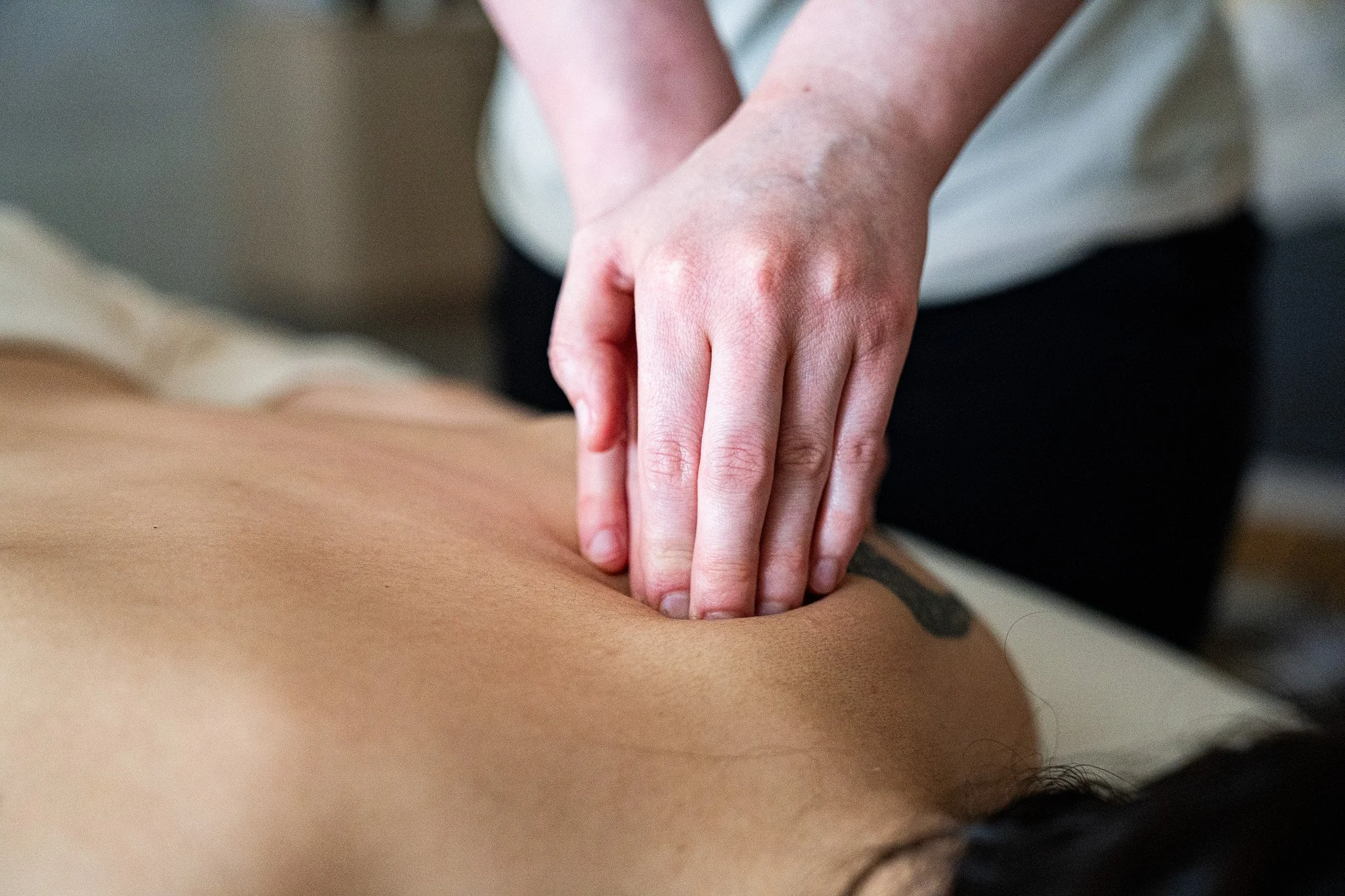A person giving a massage to another person's back, focusing on the massage technique with their hands.
