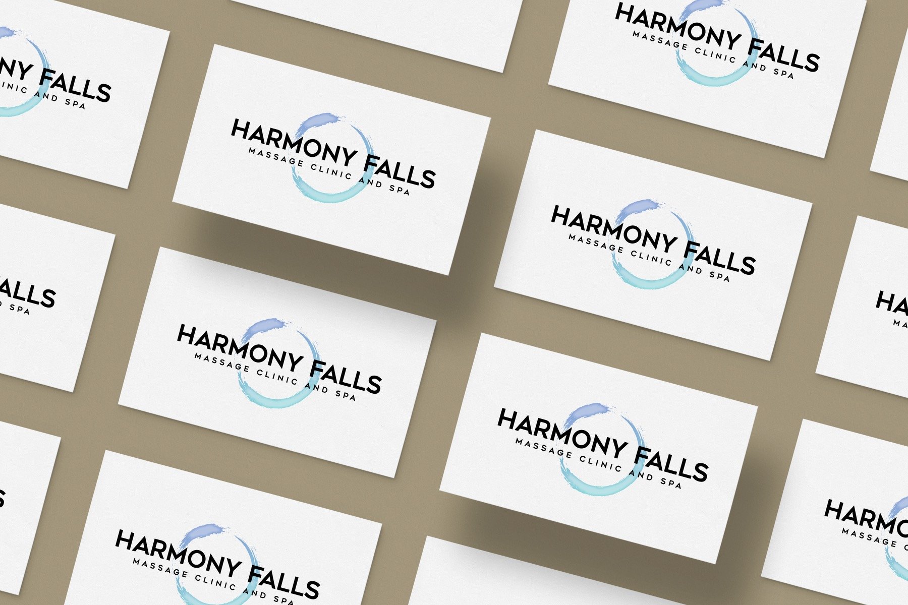 Multiple business cards for Harmony Falls Massage Clinic and Spa, arranged with a beige background. The cards feature a black text logo with a blue circular brushstroke design.