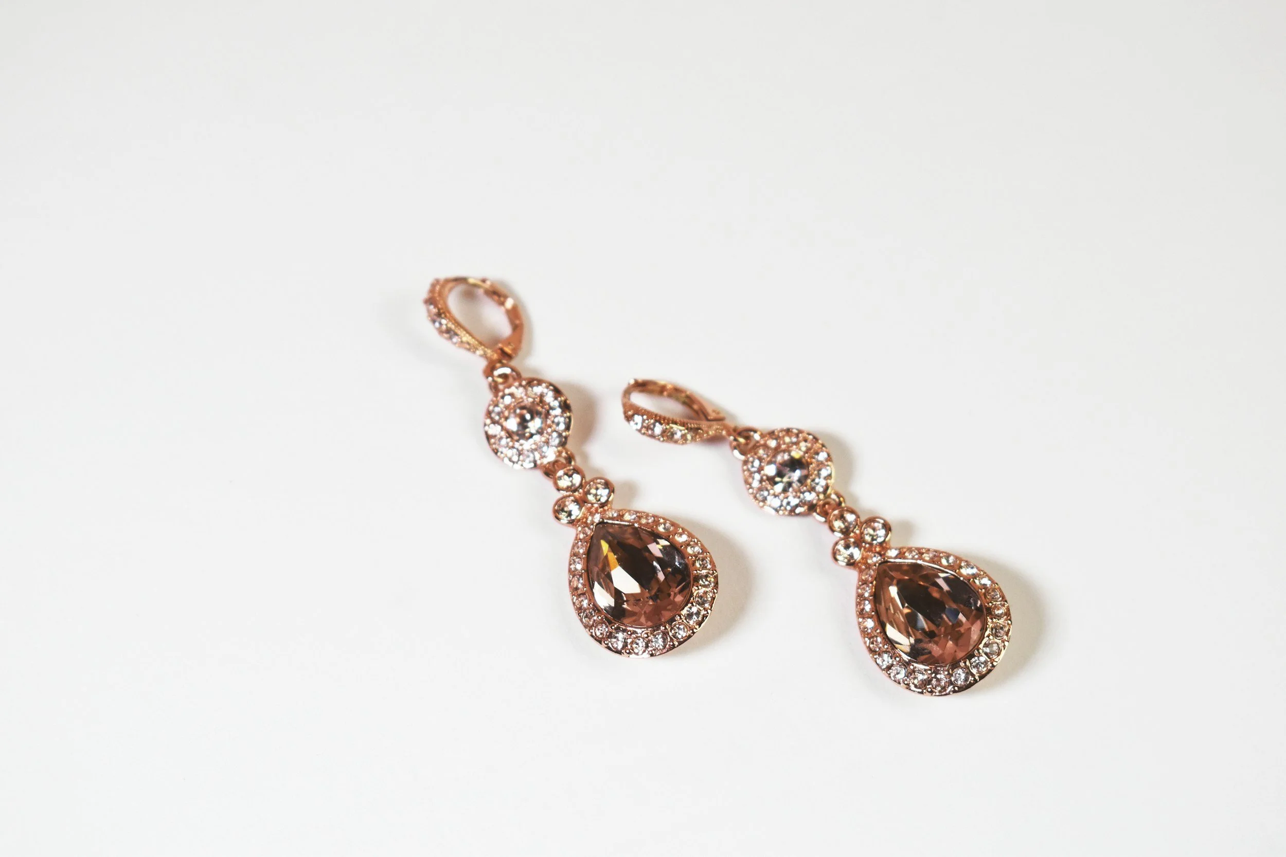 Gold and diamond studded teardrop earrings with large dark gemstones on a white background.