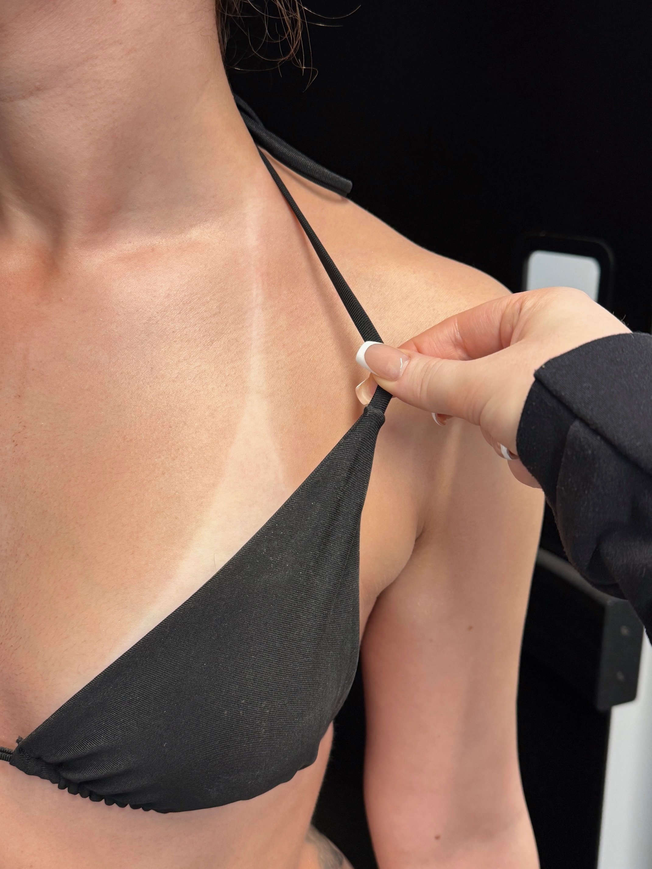 A woman adjusting a black sports bra strap.