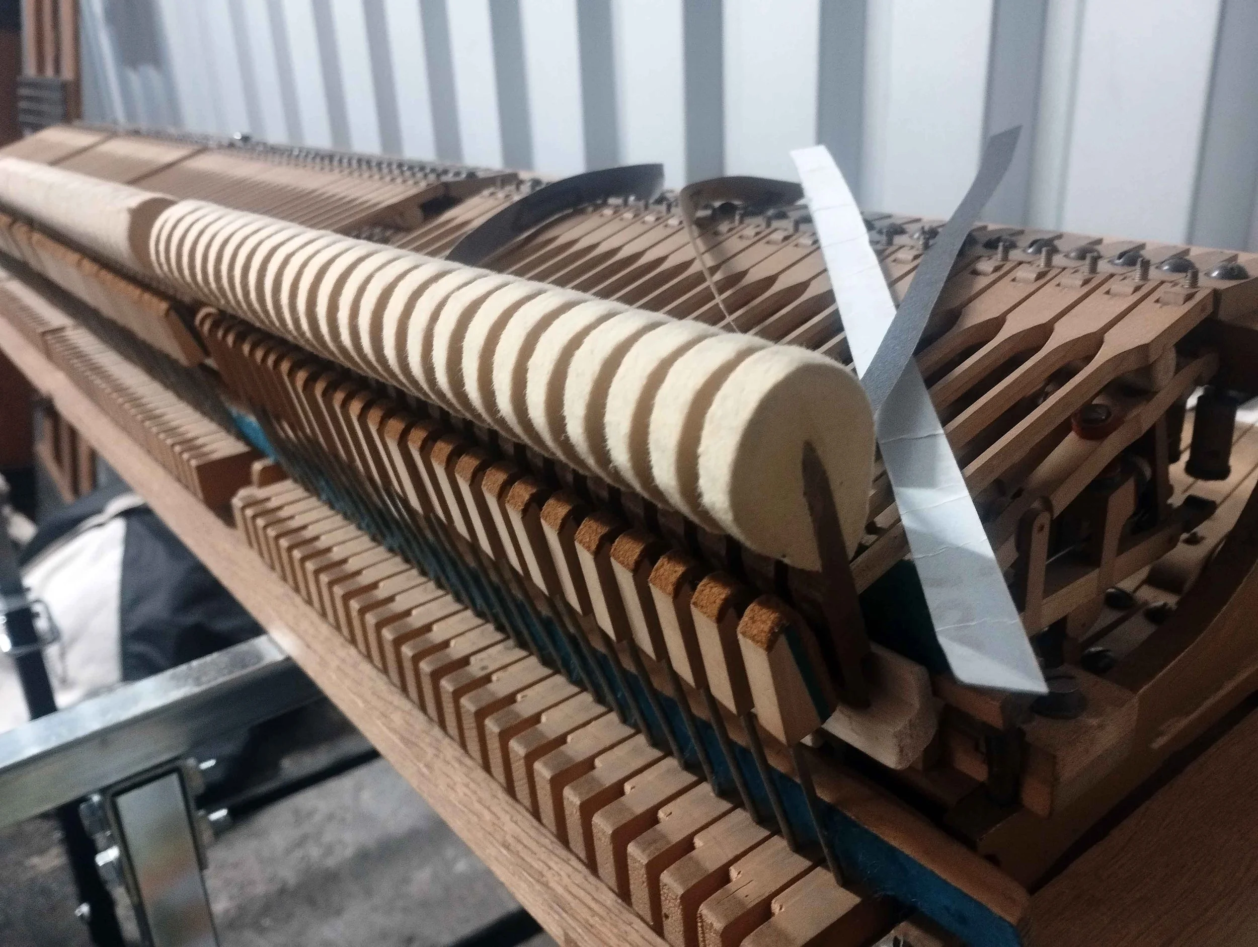 Inside view of a piano with its internal wooden hammers and strings exposed.
