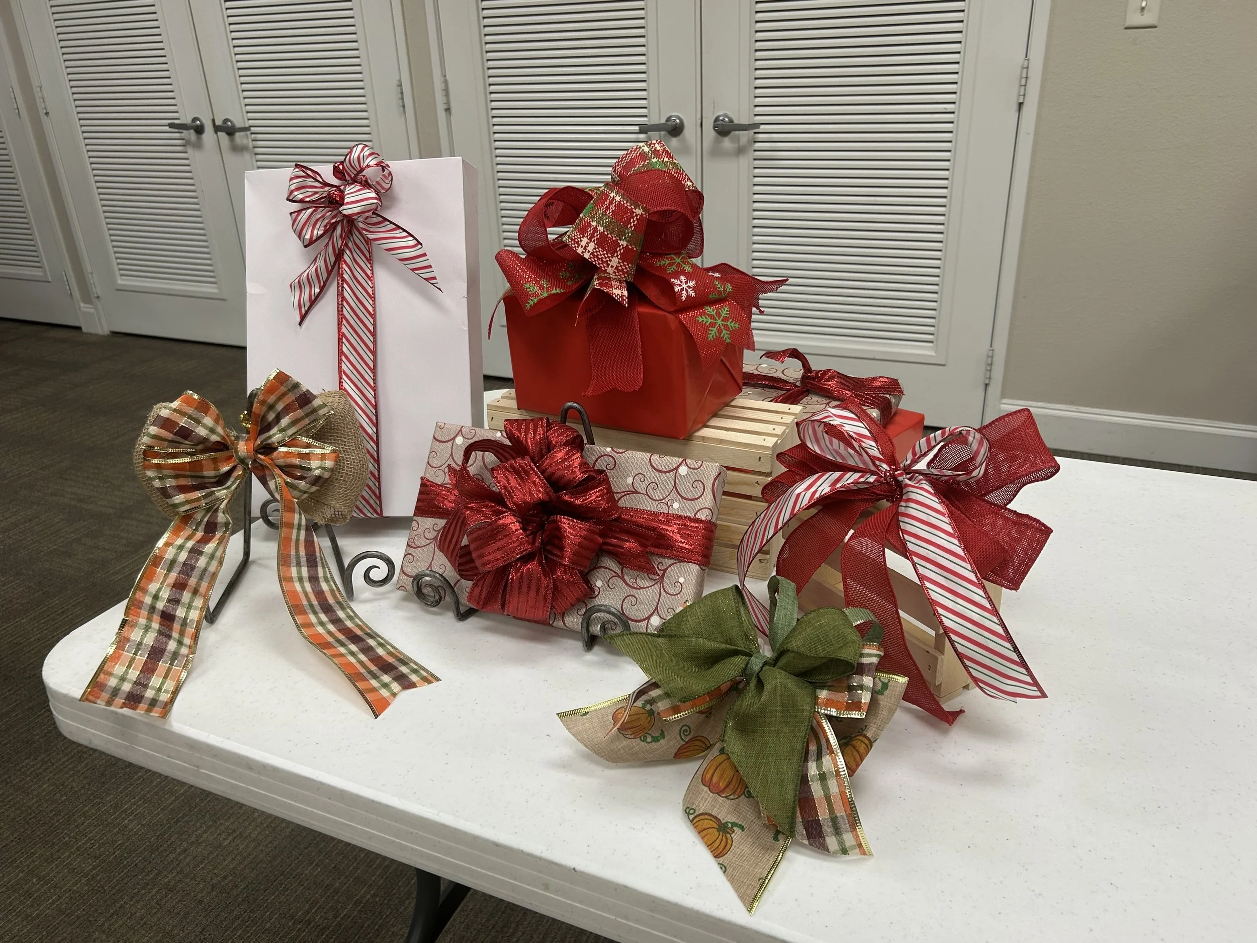 Various Christmas gift bows and ribbons displayed on a white table.