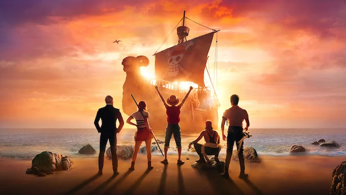 Four people standing on a beach at sunset, facing a pirate ship with a skull and crossbones flag, as the sun sets behind a mushroom-shaped cloud and a volcanic island, with rocks in the water.