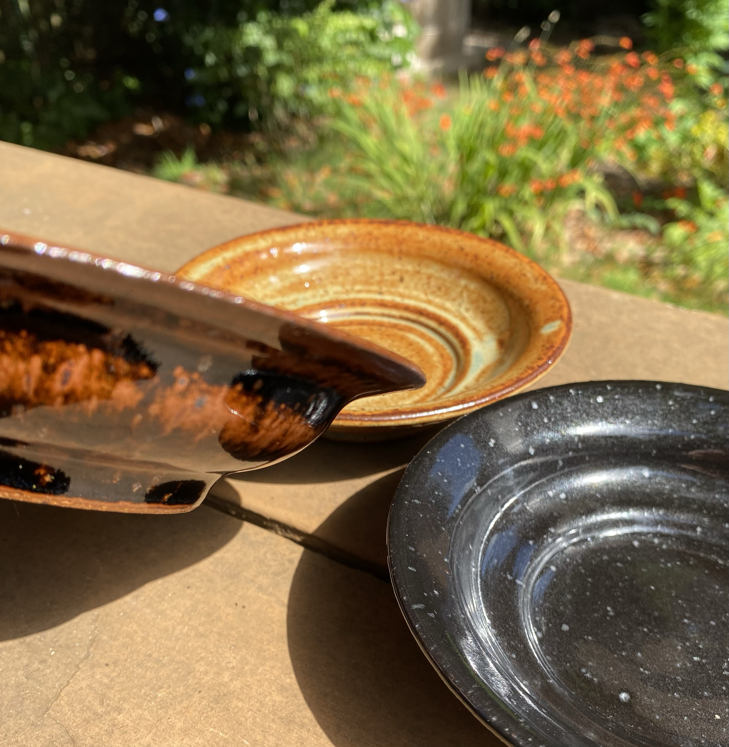 Series of mini plates, 5½" in width, recycled clay, △10 gas reduction, mirror black and tenmoku and woo blue over grey shino, 2025