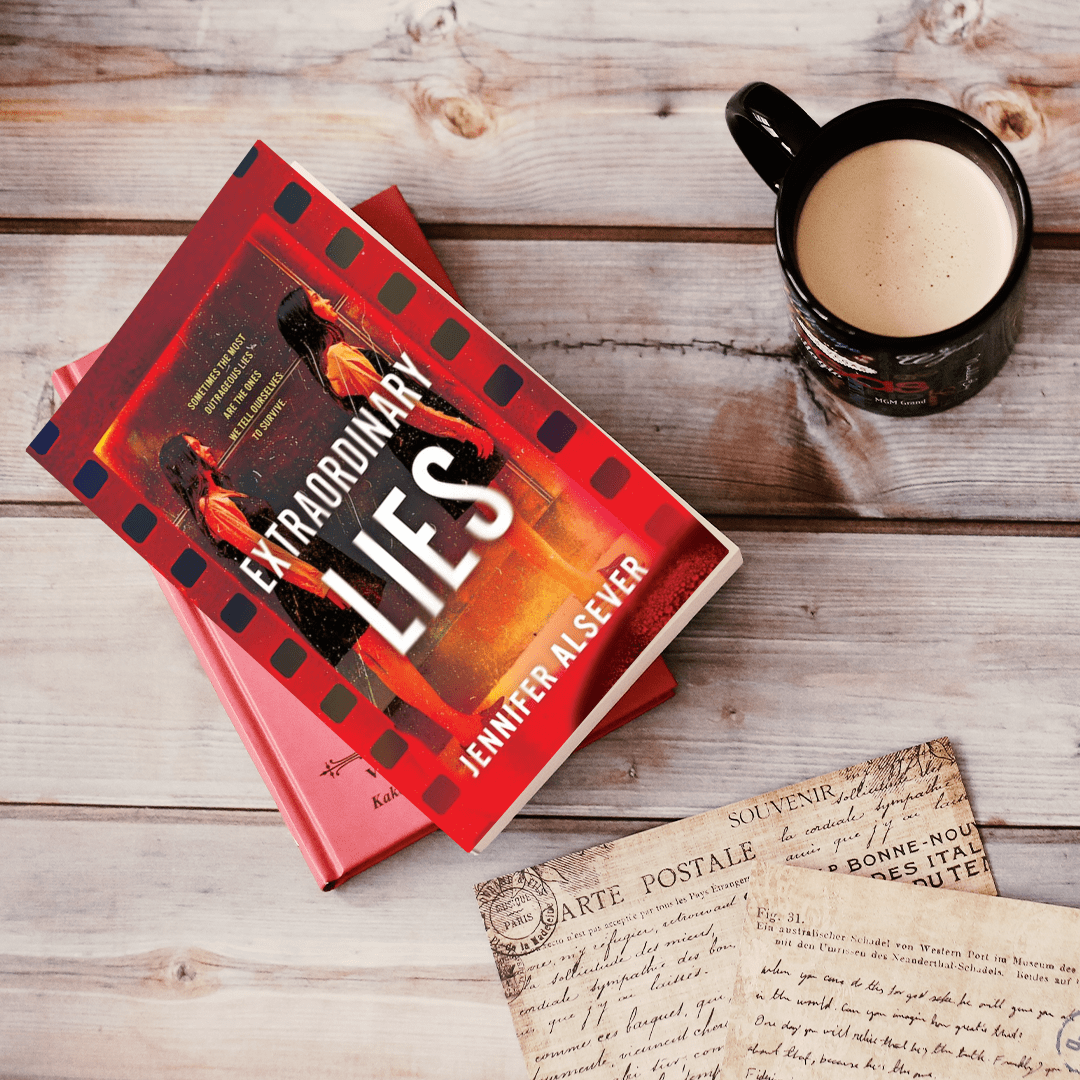 A book titled 'Extraordinary Lies' by Jennifer Alver placed on top of another pink book, a vintage postcard with handwritten text, and a black mug filled with a creamy beverage on a wooden surface.