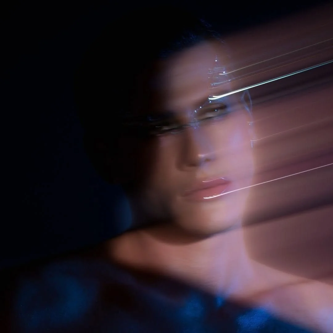 A person with glasses at night, with light streaks causing a blurred motion effect.