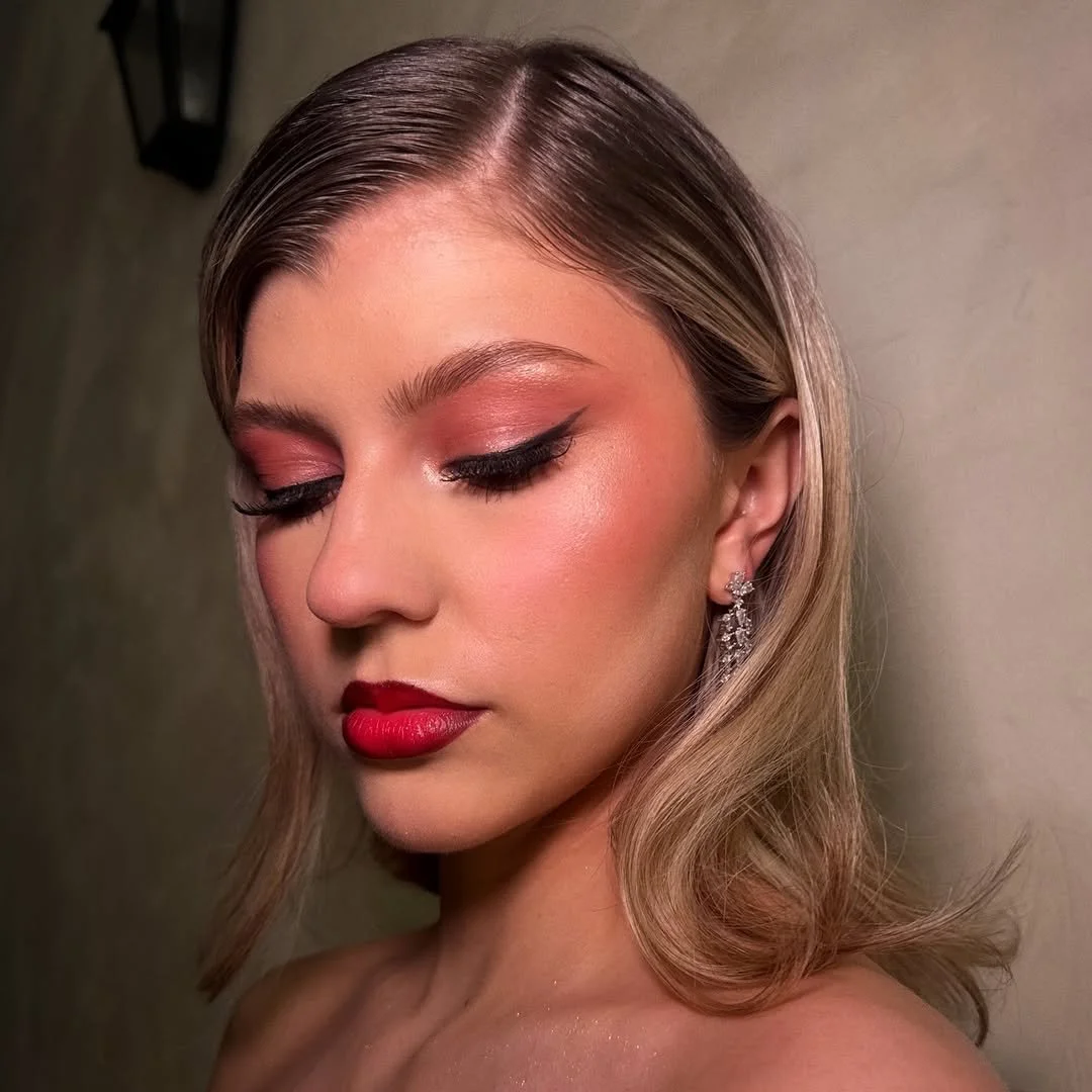 A woman with makeup and earrings, looking down with her eyes closed.