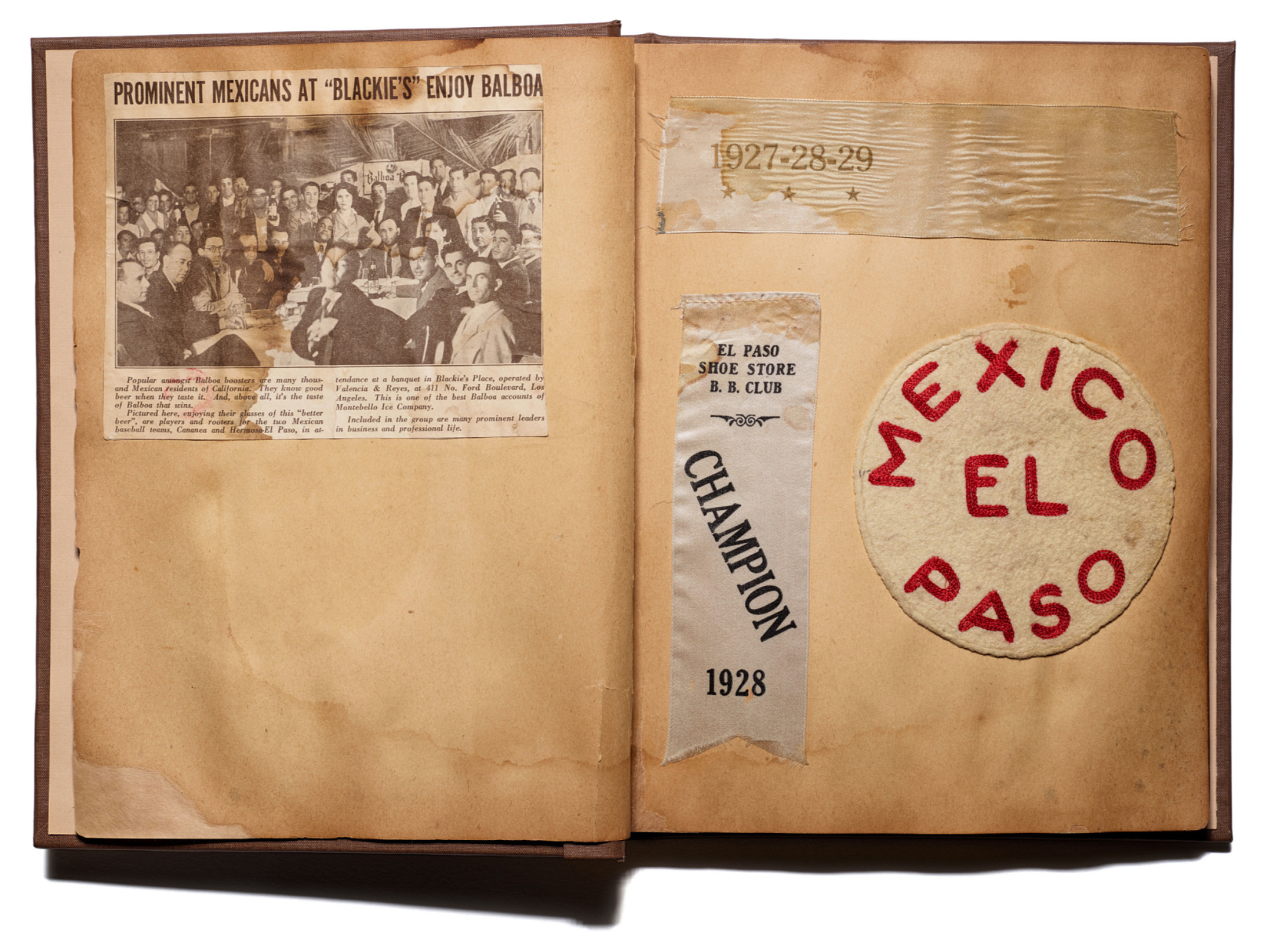 Open scrapbook displaying a vintage newspaper clipping about prominent Mexicans at 'Blackie's,' a Balboa restaurant, with a black-and-white photo of a group of people sitting at a table, and various old paper labels and patches on the pages.