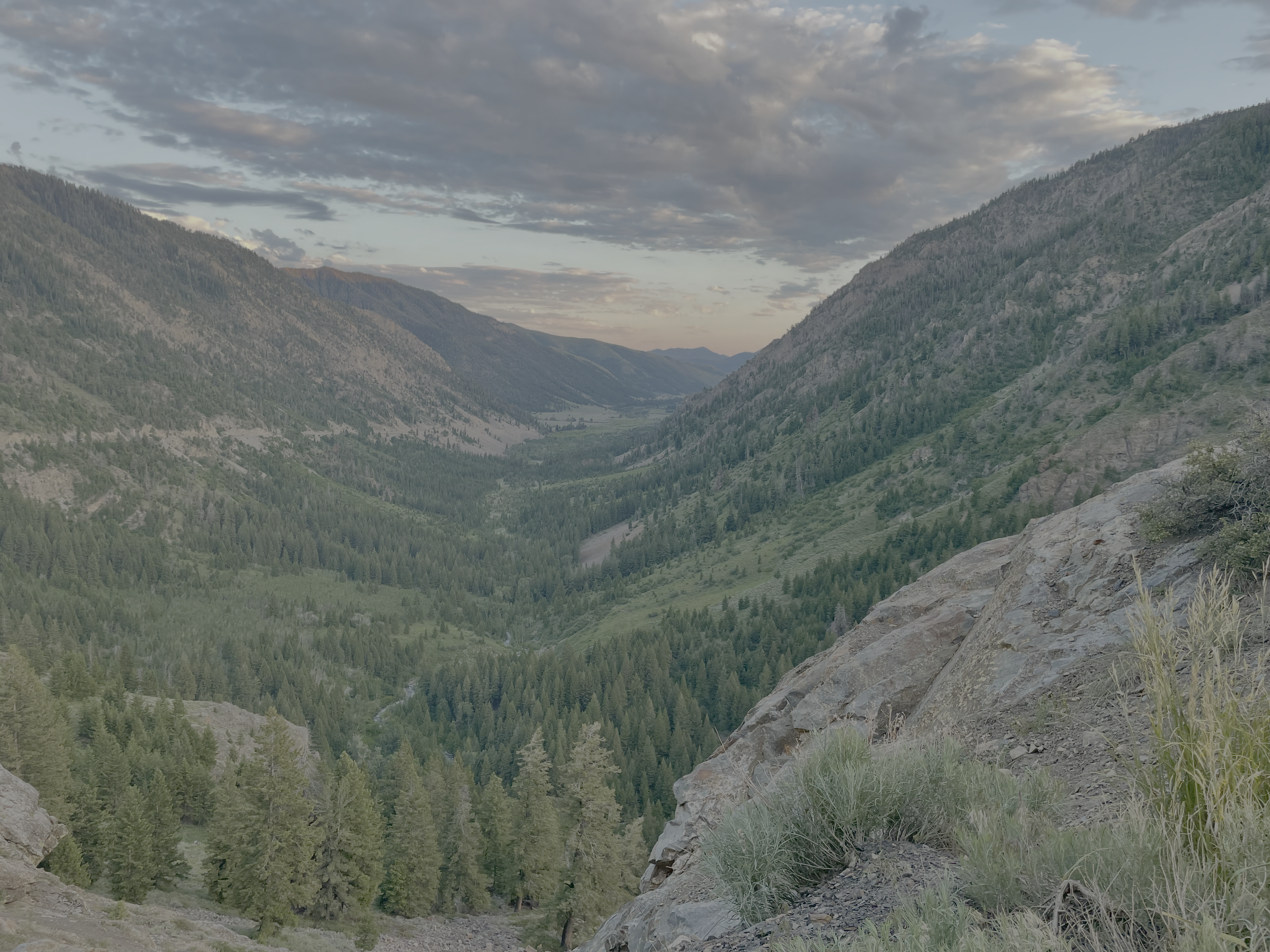 A view of a green valley between mountains with partly cloudy sky.