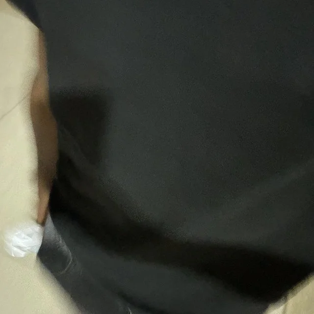 Close-up of a person wearing a black shirt and gray pants, with part of the arm and side visible.