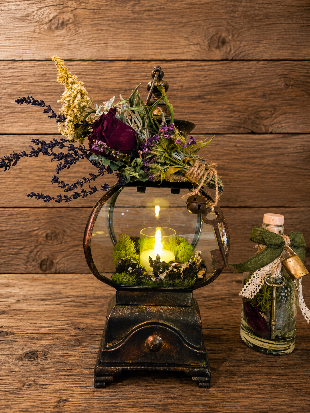 SOLD — The Hearth Keeper

An old-world lantern transformed into a piece of woodland art, crowned with dried botanicals and gathered forest elements. Moss surrounds the warm glow within, while an aged key and small bell hang at its side like remnants 