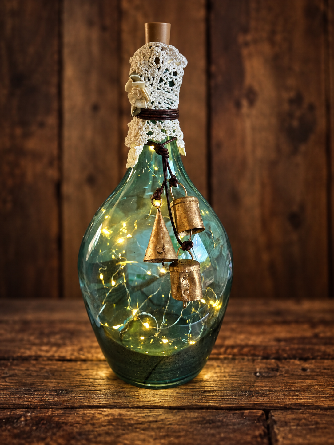 The Bellkeeper’s Glow

A turquoise glass bottle wrapped in old lace and rustic twine, with glowing fairy lights and three weathered brass bells. Inspired by the old belief that light and ringing bells could guide weary wanderers safely home.
