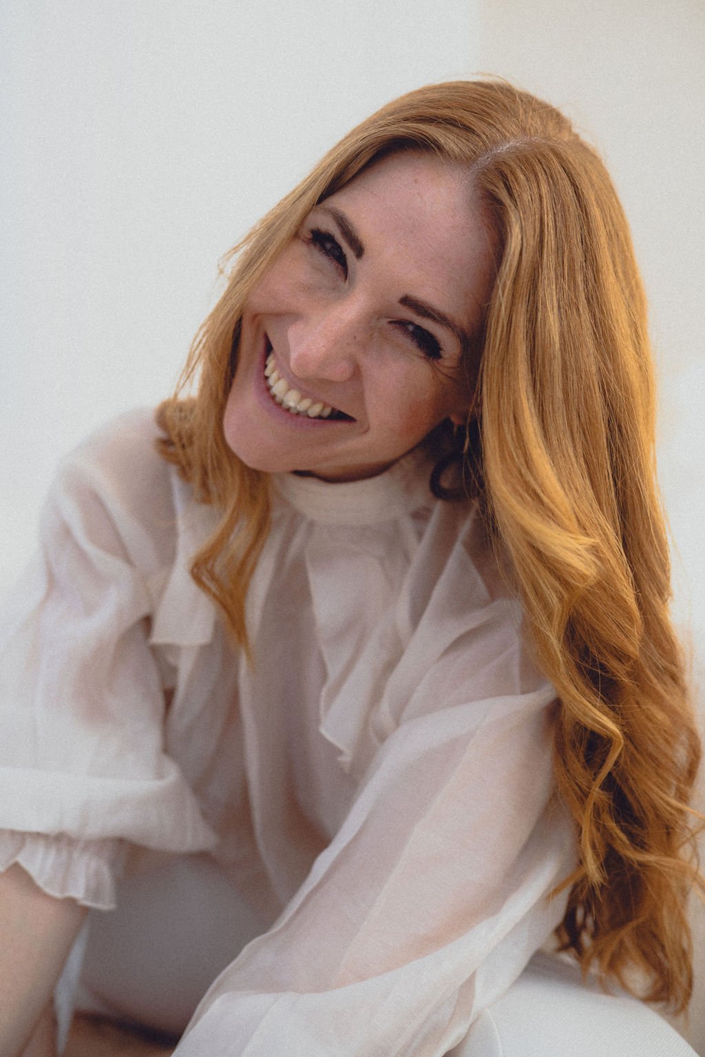 Alexandra Dersch, Moderatorin, Kommentatorin, ZDF, Leichtathletik, Curling, Para Ski Alpin, Skispringen, Lächelnde Frau mit roten Haaren, weiße Bluse, auf hellem Hintergrund.