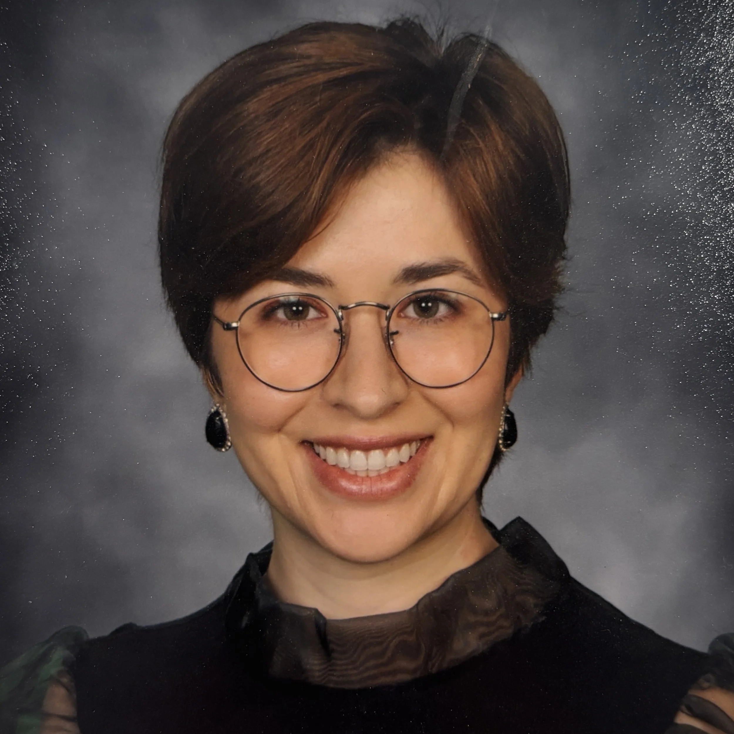 Headshot of smiling female tutor with short brown hair wearing a black shirt.