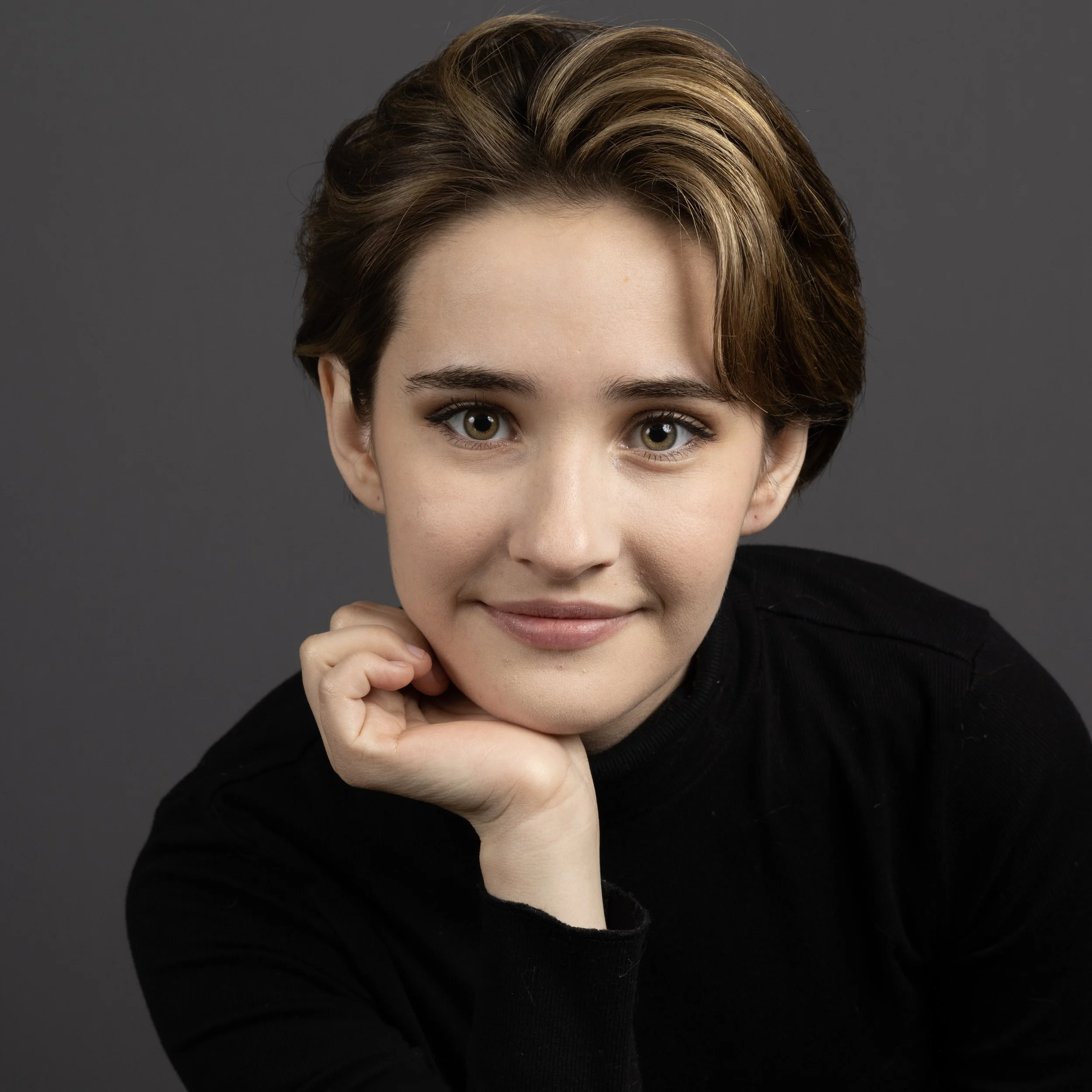Headshot of smiling nonbinary tutor with short brown hair with highlights wearing a black shirt.