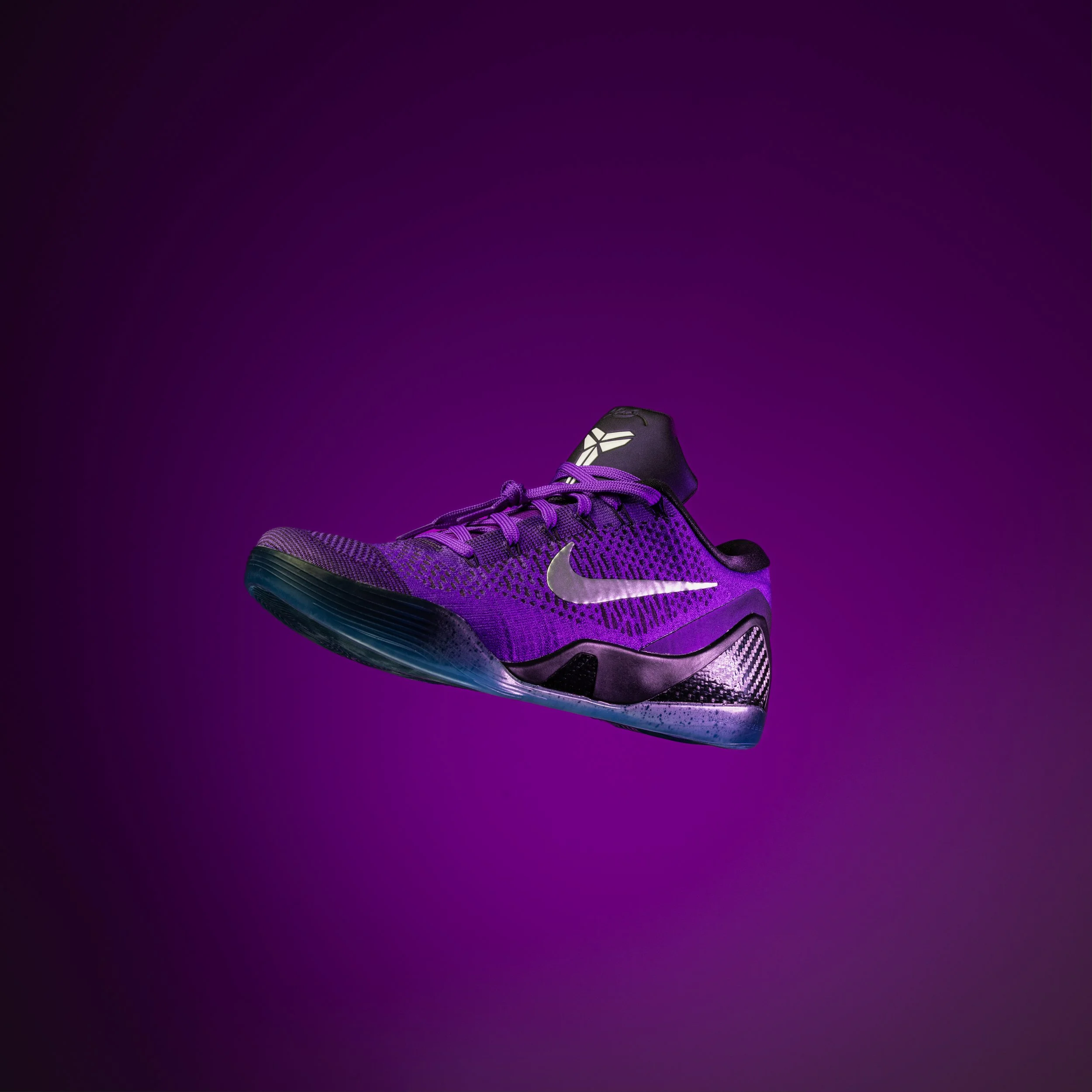 A purple and black athletic shoe with a Nike swoosh logo against a purple background.