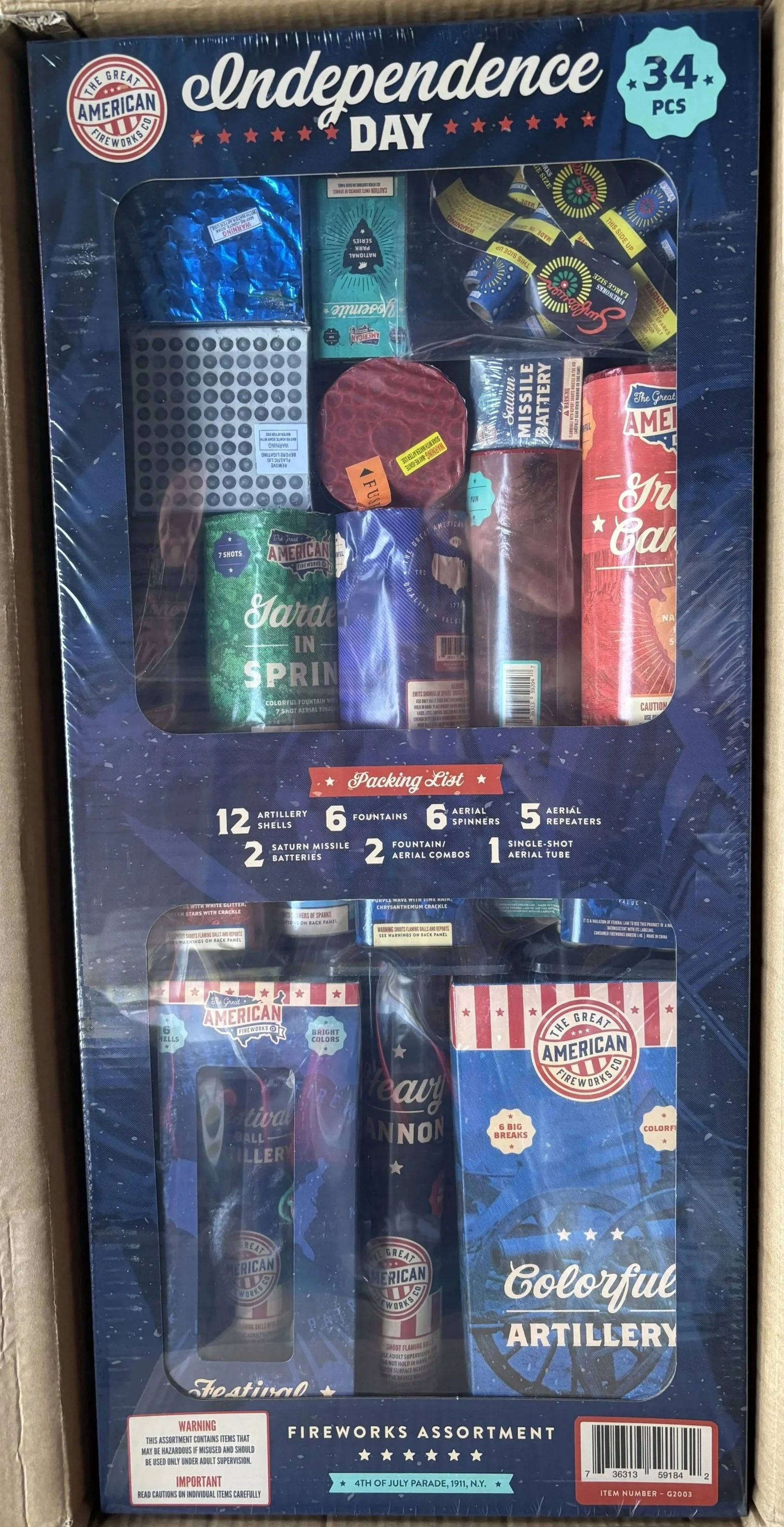 Box of American Independence Day fireworks with 34 pieces, including artillery shells, fountains, aerial spinners, aerial repeaters, and batteries, featuring colorful packaging and a July 4th theme.