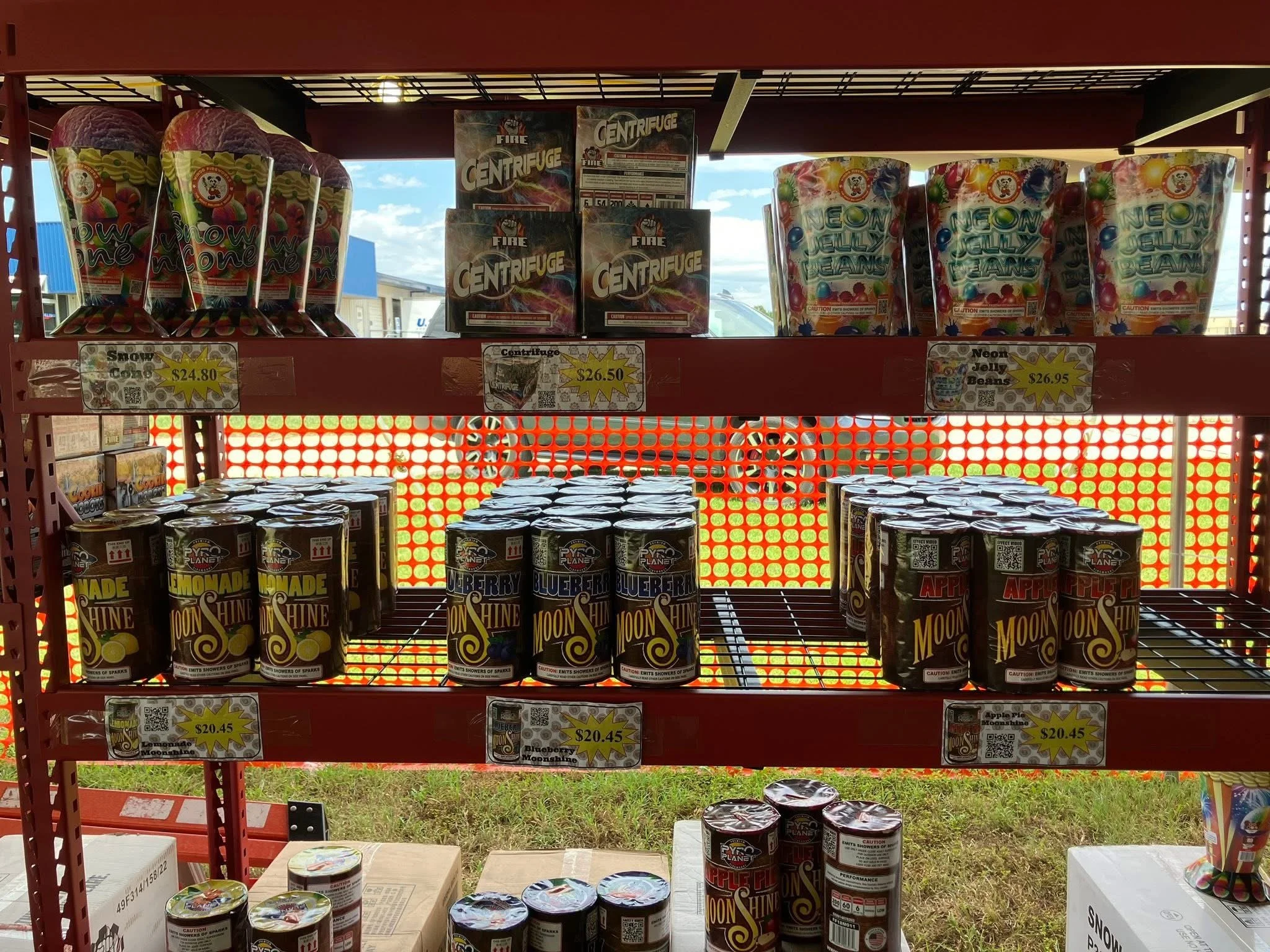 Display shelf with fireworks products including Snow Cone, Centrifuge, Neon Jelly Beans, Lemonade Moonshine, Blueberry Moonshine, Apple Pie Moonshine, and their prices.