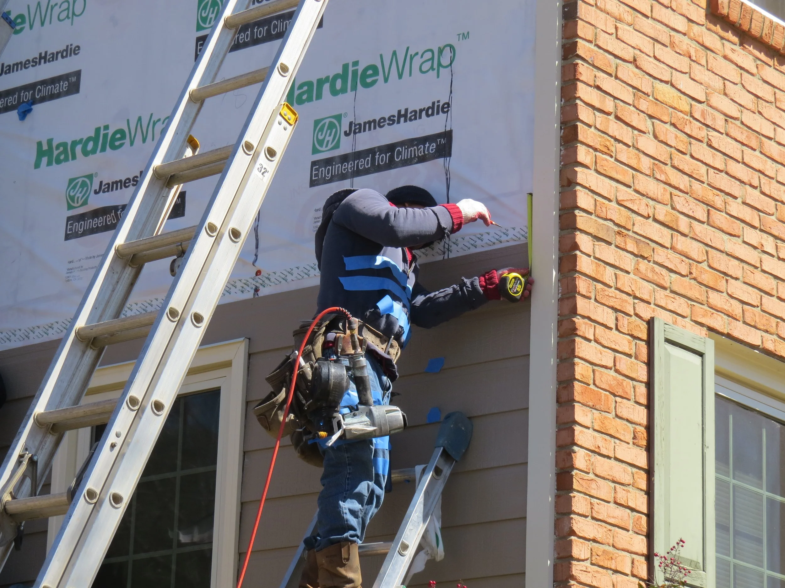 Installer verifying proper siding reveal spacing during Hardie fiber cement siding installation.